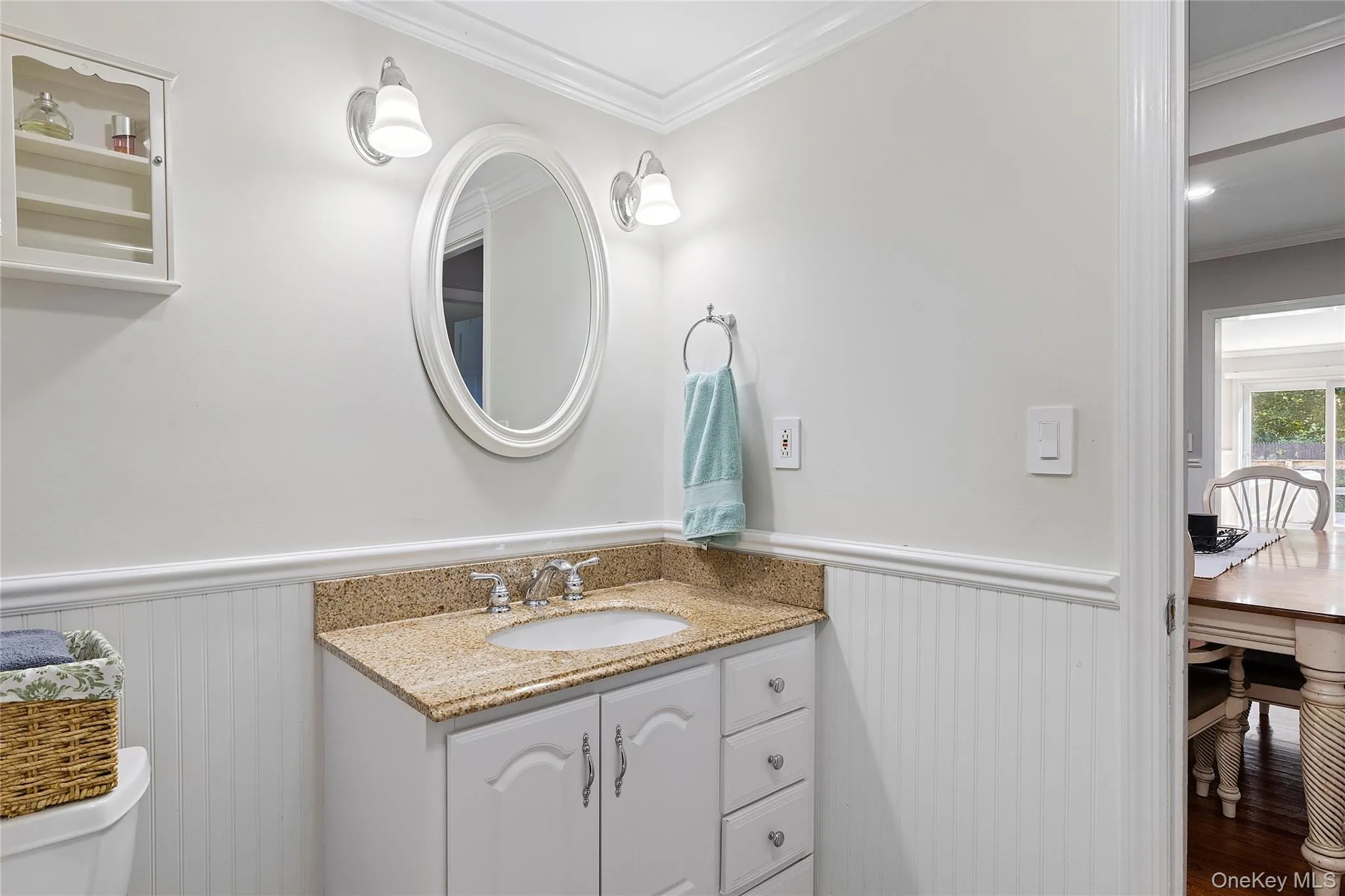 Half bathroom featuring crown molding, vanity, and wainscoting Half bathroom featuring crown molding, vanity, and wainscoting