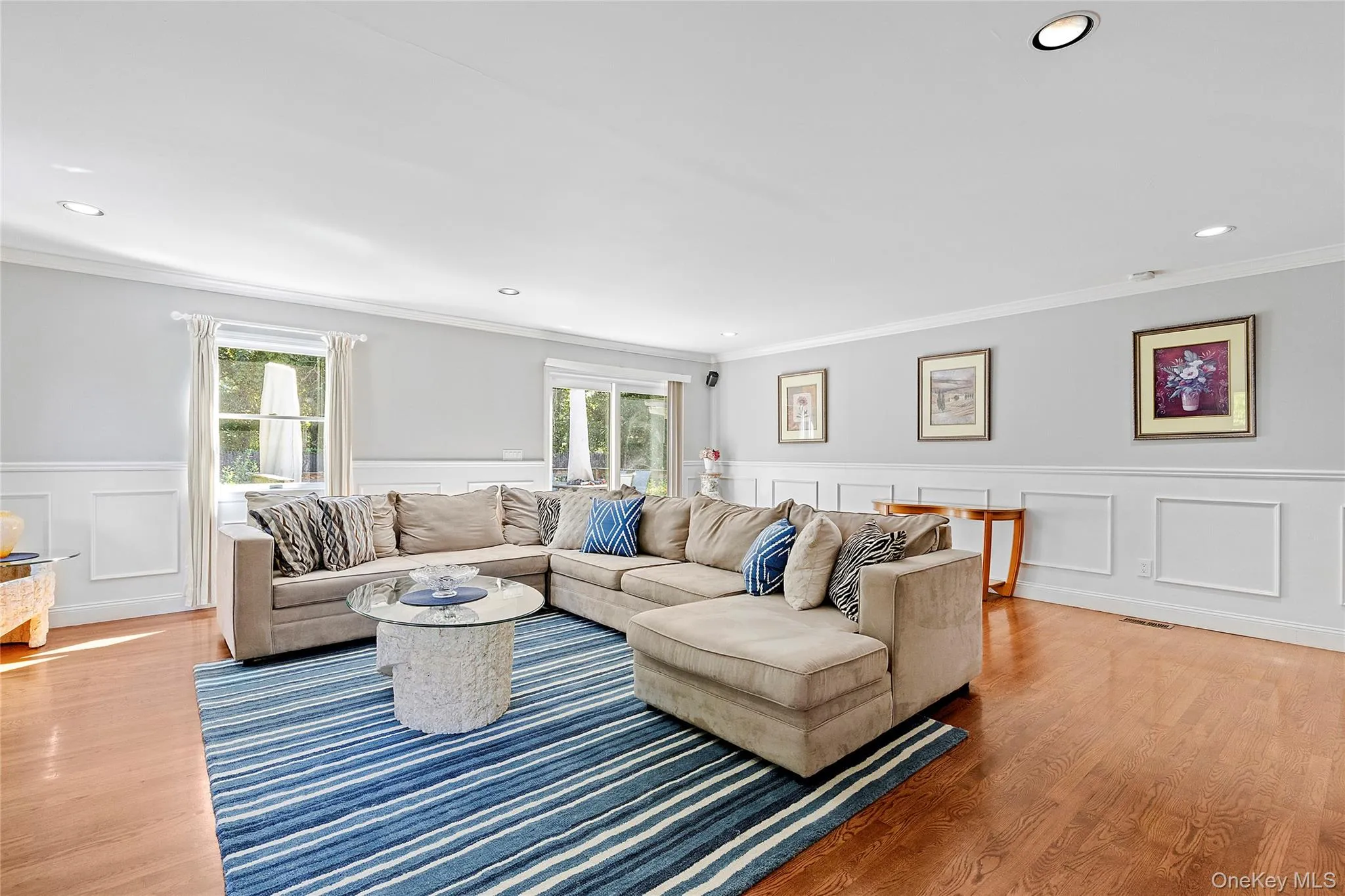 Living area with crown molding, recessed lighting, light wood finished floors, and a decorative wall Living area with crown molding, recessed lighting, light wood finished floors, and a decorative wall