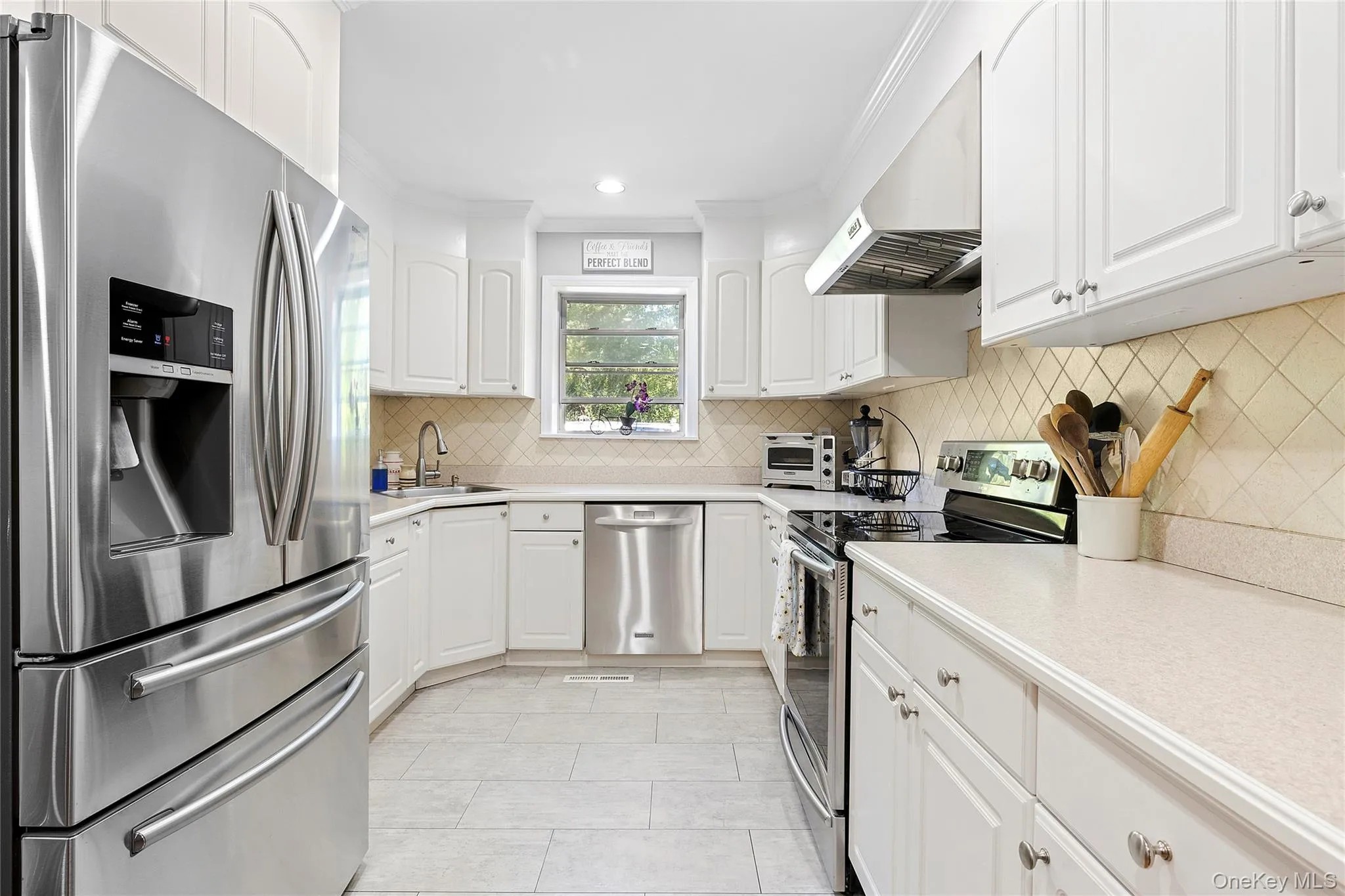 Kitchen featuring appliances with stainless steel finishes, white cabinets, light countertops, range hood, and recessed lighting Kitchen featuring appliances with stainless steel finishes, white cabinets, light countertops, range hood, and recessed lighting