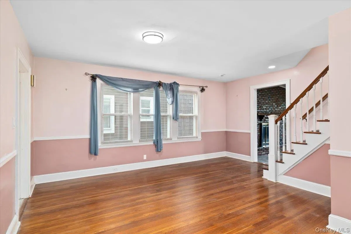 Unfurnished room with dark wood-style floors and stairway Unfurnished room with dark wood-style floors and stairway