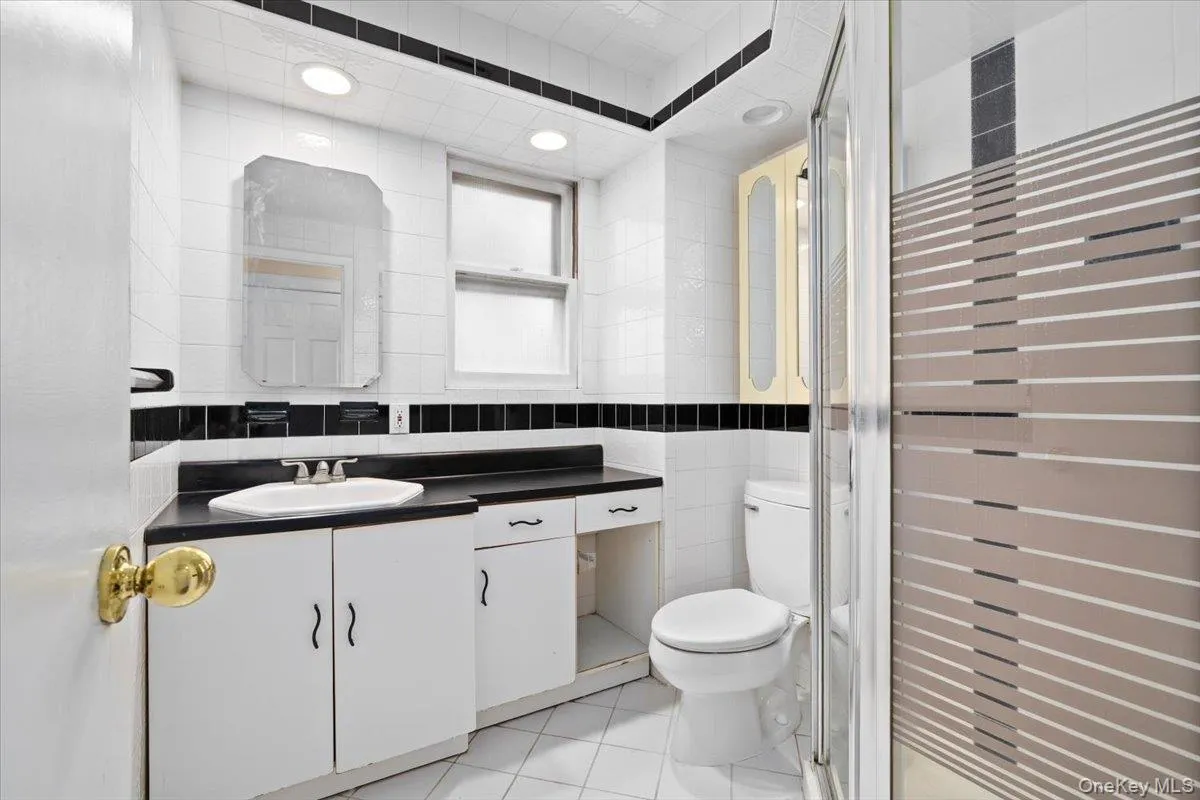 Full bath featuring tile walls, vanity, light tile patterned floors, and a shower stall Full bath featuring tile walls, vanity, light tile patterned floors, and a shower stall