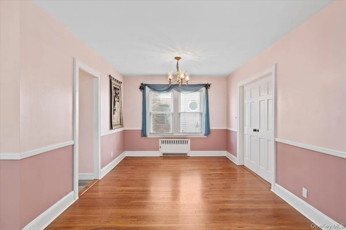 Unfurnished dining area featuring light wood-style flooring, a chandelier, and radiator heating unit Unfurnished dining area featuring light wood-style flooring, a chandelier, and radiator heating unit