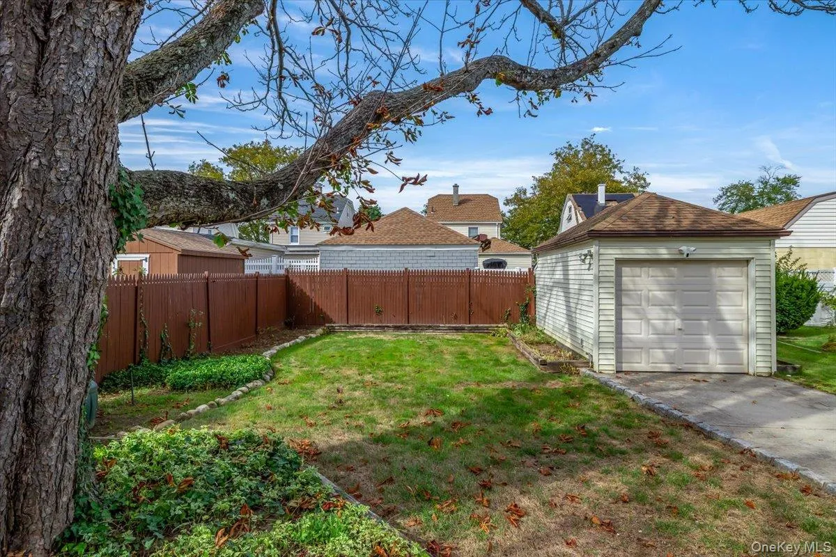 Fenced backyard featuring an outdoor structure and concrete driveway Fenced backyard featuring an outdoor structure and concrete driveway