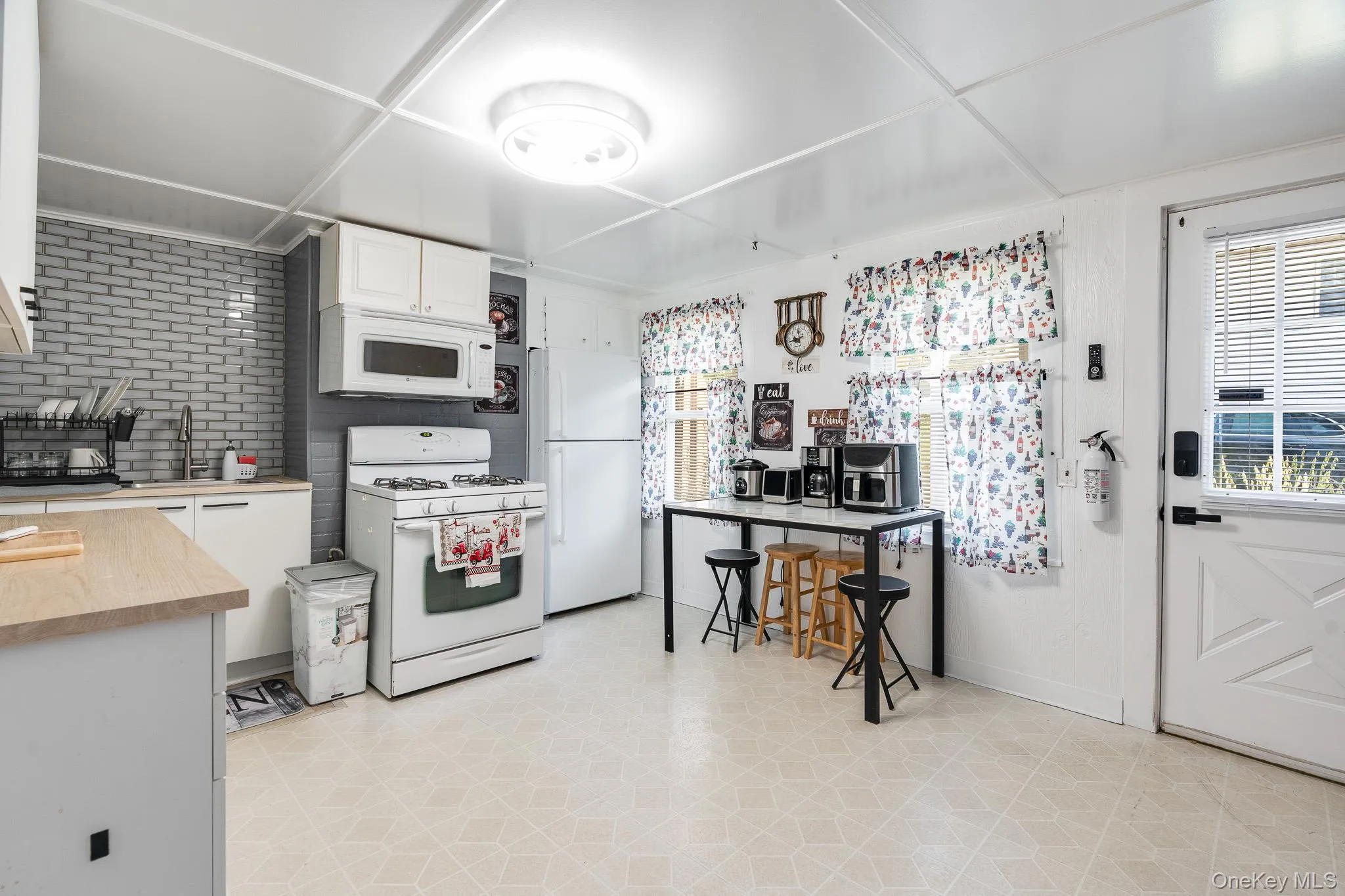 Kitchen with white cabinets, white appliances, light flooring, and butcher block counters Kitchen with white cabinets, white appliances, light flooring, and butcher block counters