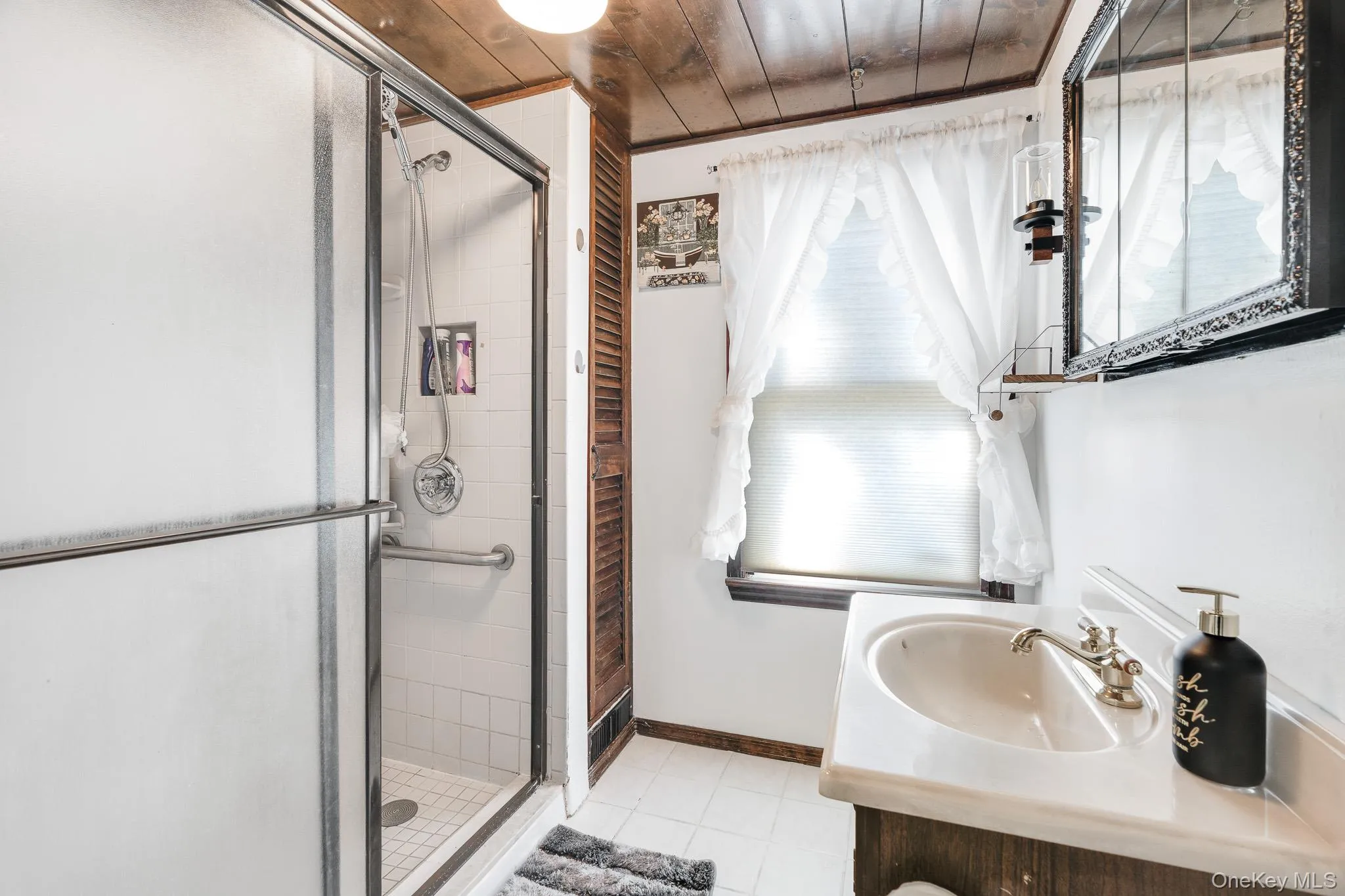 Bathroom with a shower stall, vanity, light tile patterned floors, and wooden ceiling Bathroom with a shower stall, vanity, light tile patterned floors, and wooden ceiling