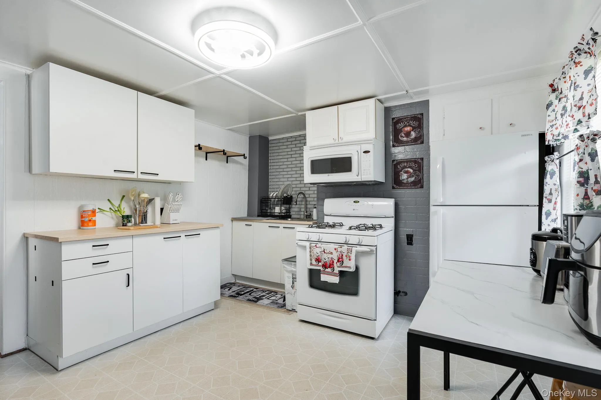 Kitchen with white appliances, white cabinets, light countertops, and light flooring Kitchen with white appliances, white cabinets, light countertops, and light flooring