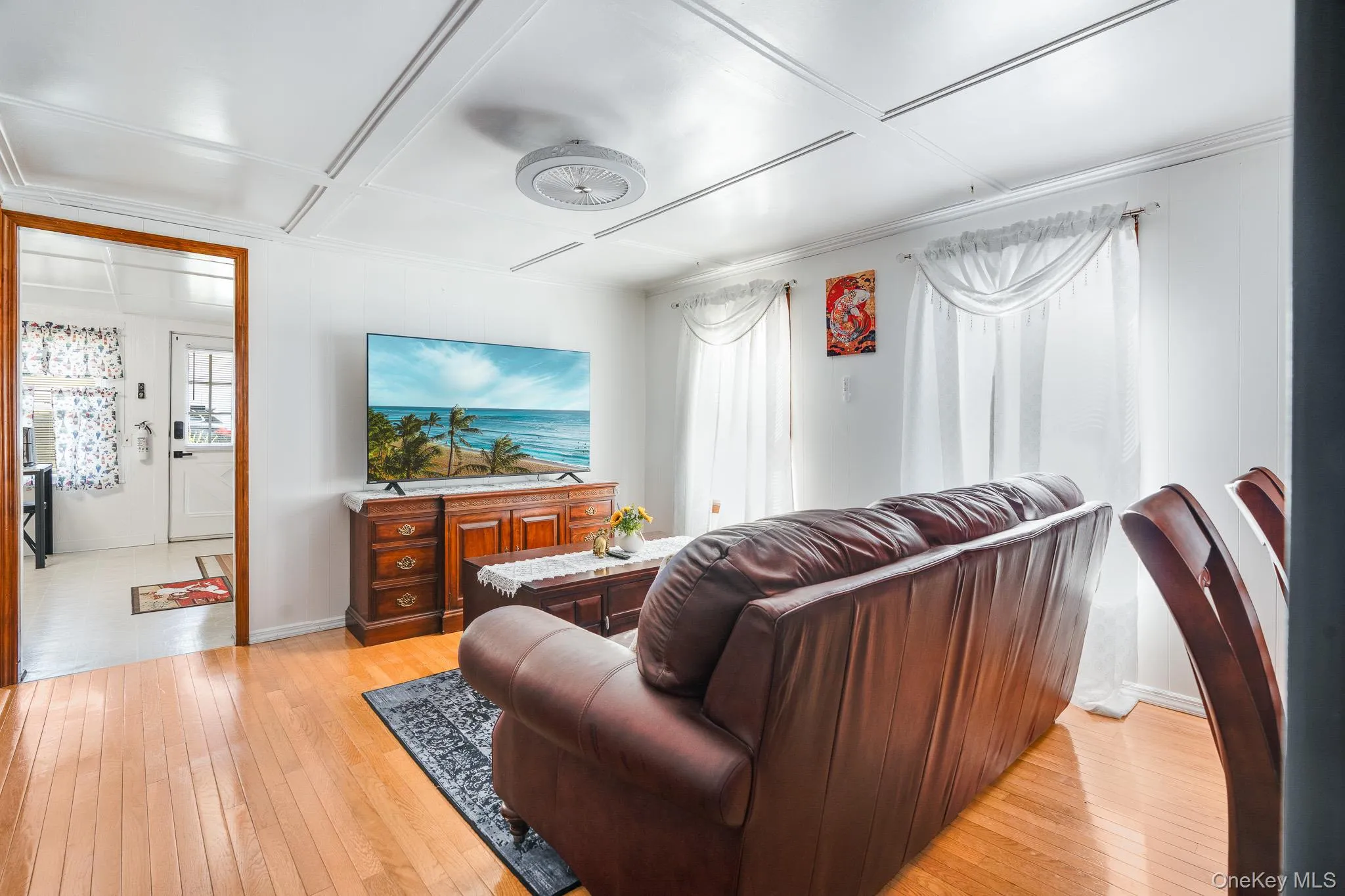 Living area featuring light wood-style floors and coffered ceiling Living area featuring light wood-style floors and coffered ceiling