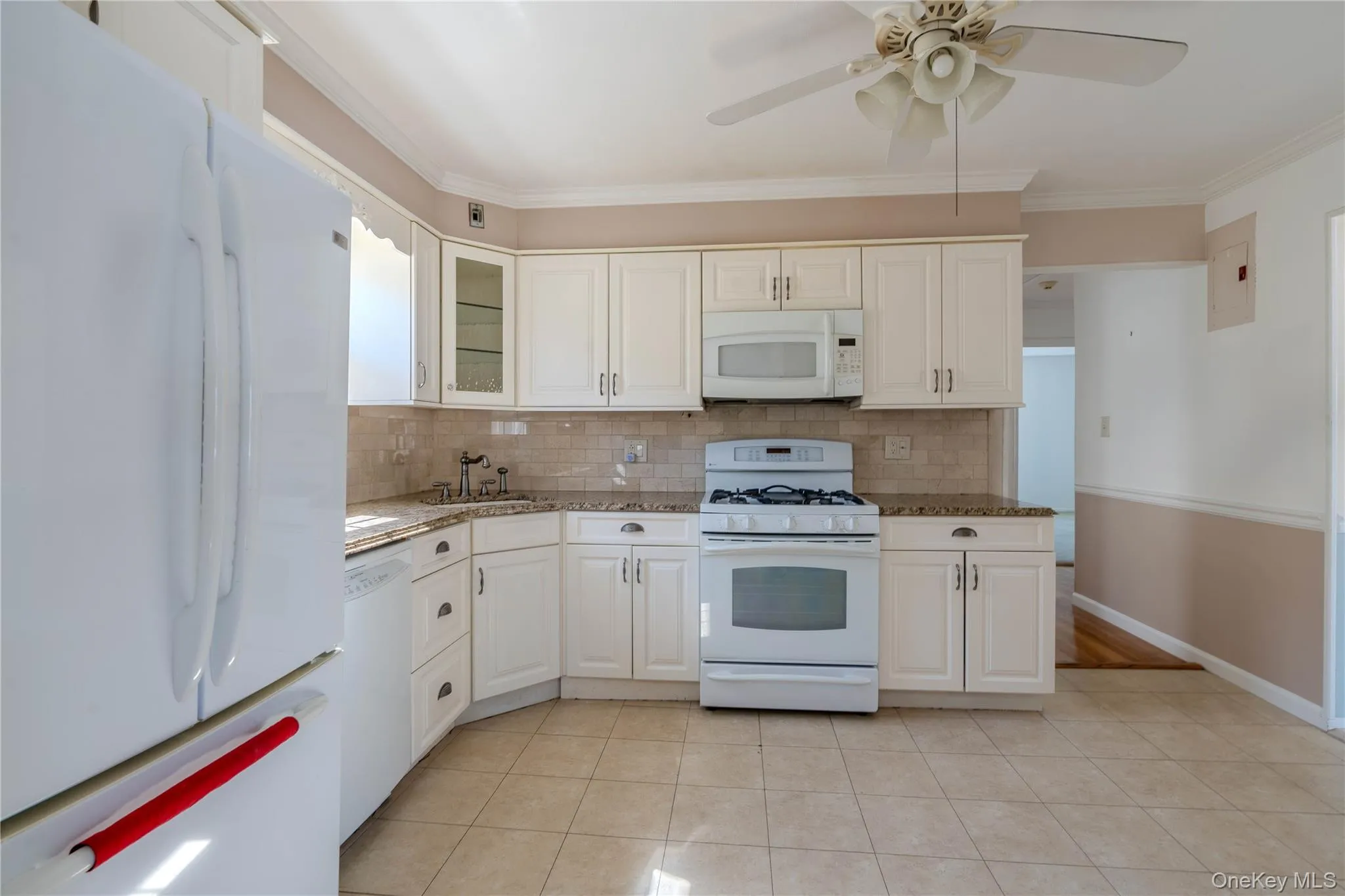 Kitchen featuring white appliances, backsplash, glass insert cabinets, light tile patterned flooring, and crown molding Kitchen featuring white appliances, backsplash, glass insert cabinets, light tile patterned flooring, and crown molding