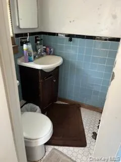 Bathroom featuring tile walls, vanity, and wainscoting Bathroom featuring tile walls, vanity, and wainscoting