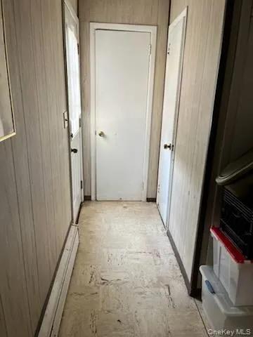 Hall featuring wood walls and a baseboard radiator Hall featuring wood walls and a baseboard radiator