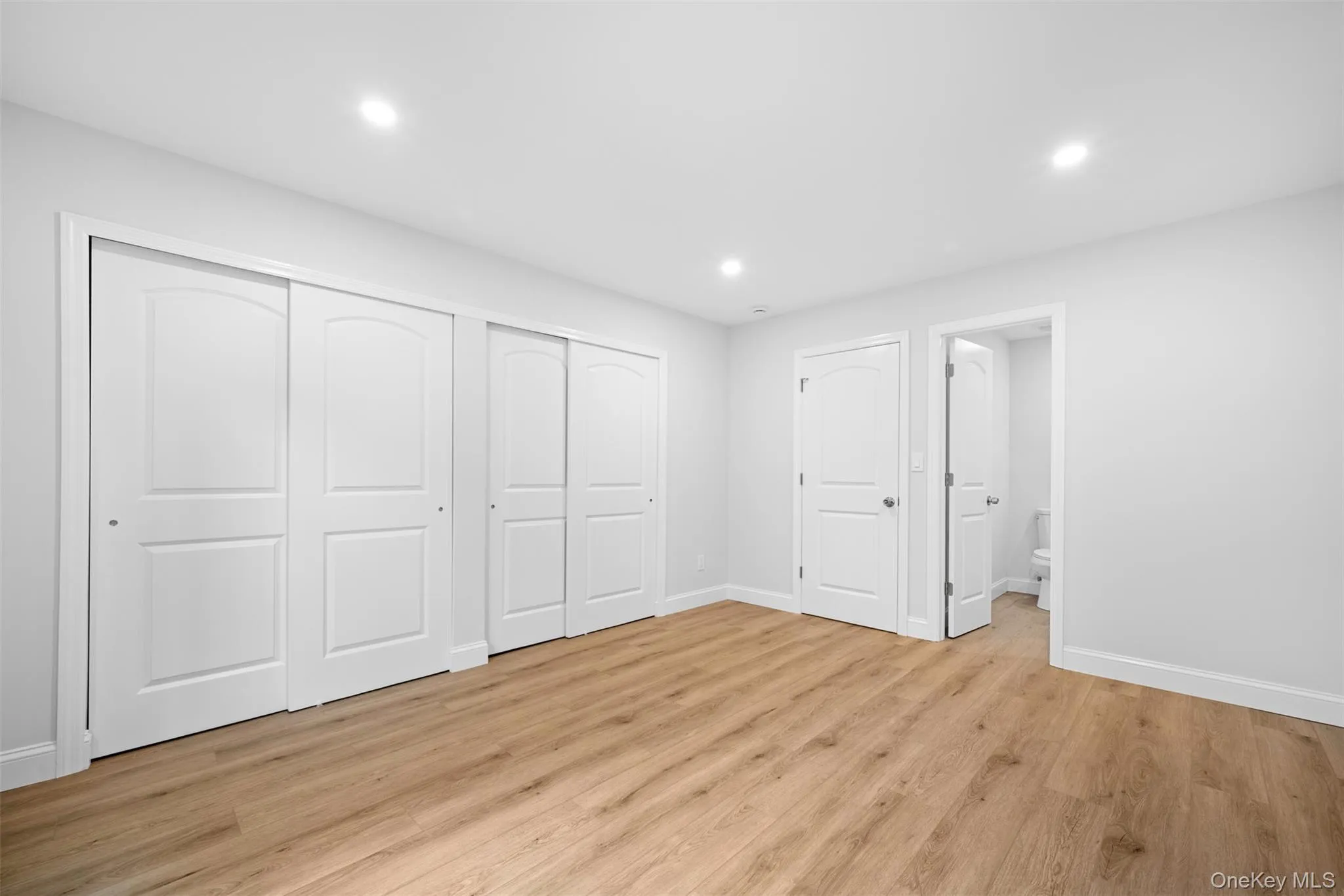 Unfurnished bedroom with light wood-type flooring, recessed lighting, a closet, and connected bathroom Unfurnished bedroom with light wood-type flooring, recessed lighting, a closet, and connected bathroom