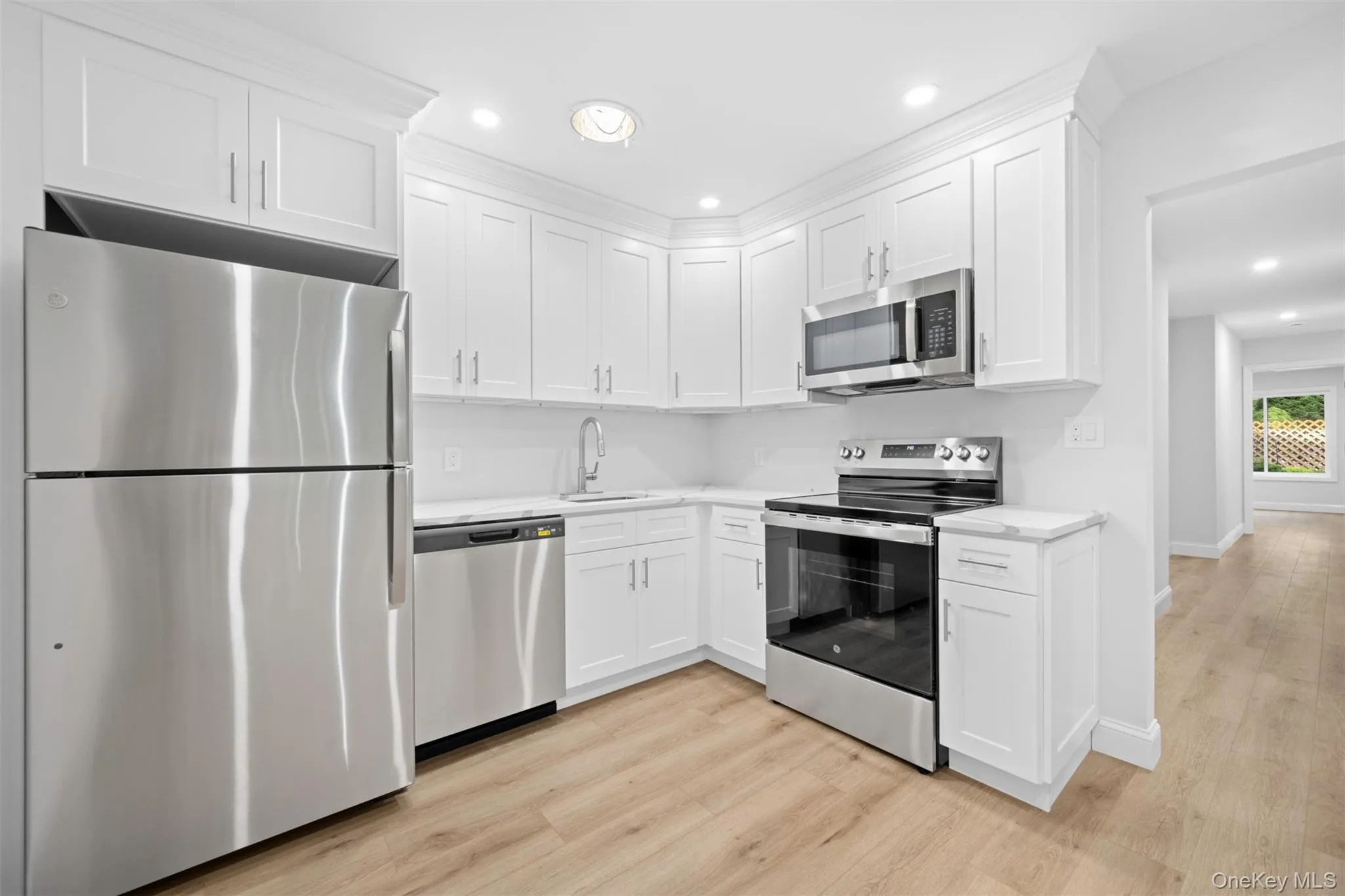 Kitchen featuring stainless steel appliances, white cabinets, recessed lighting, and light wood finished floors Kitchen featuring stainless steel appliances, white cabinets, recessed lighting, and light wood finished floors