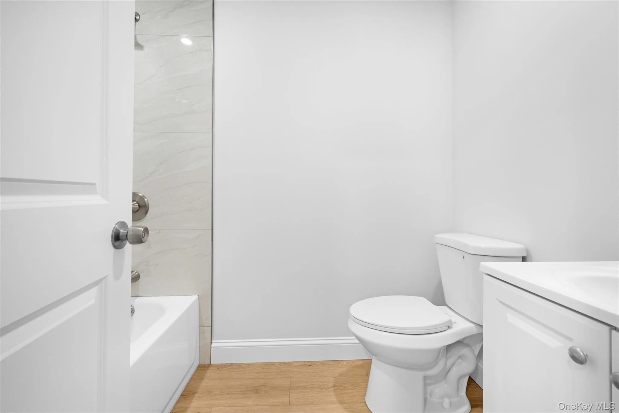 Full bath featuring vanity, bathtub / shower combination, and light wood finished floors Full bath featuring vanity, bathtub / shower combination, and light wood finished floors