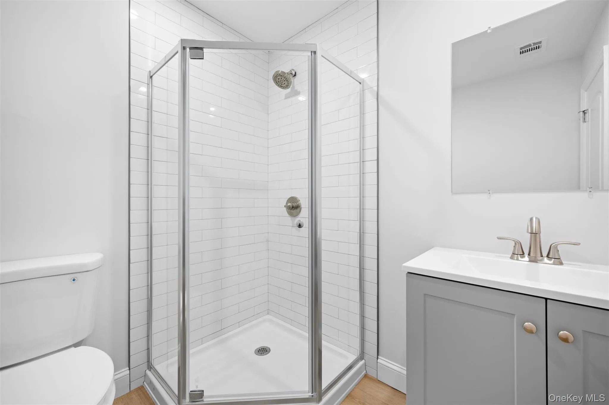 Full bathroom with a stall shower, vanity, and light wood finished floors Full bathroom with a stall shower, vanity, and light wood finished floors