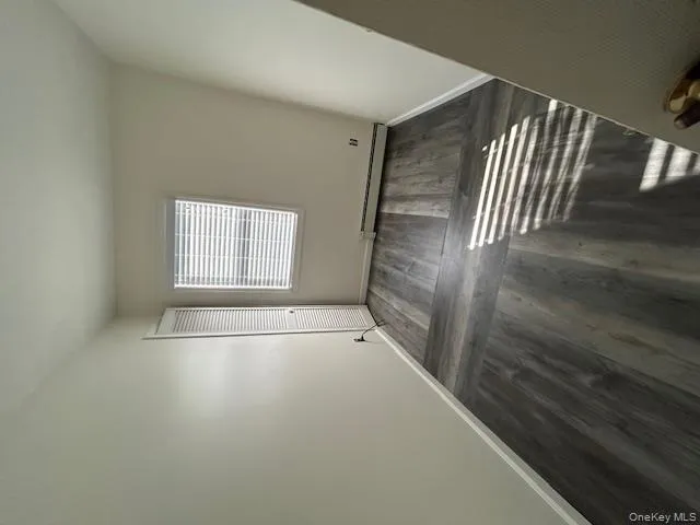 Spare room with dark wood-type flooring and a baseboard heating unit Spare room with dark wood-type flooring and a baseboard heating unit