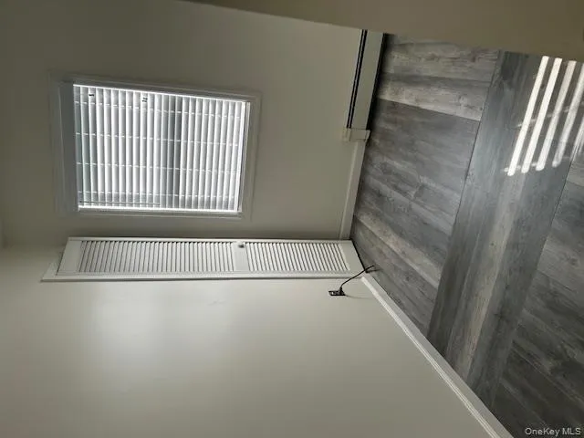 Unfurnished bedroom featuring baseboard heating and dark wood-style flooring Unfurnished bedroom featuring baseboard heating and dark wood-style flooring