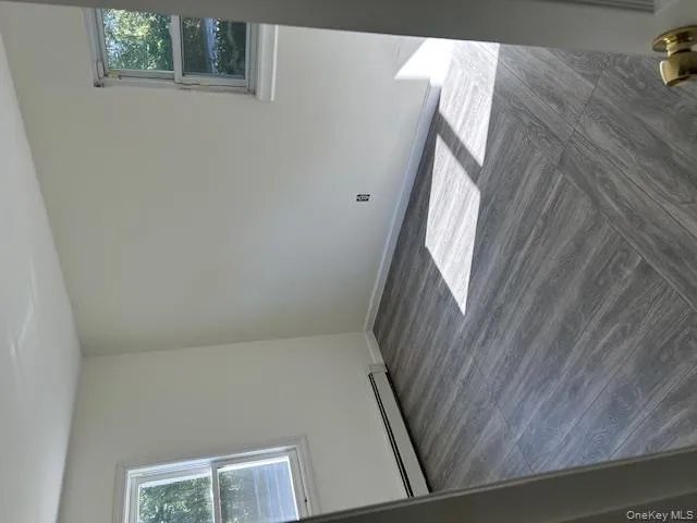 Unfurnished room with a baseboard radiator and dark wood-type flooring Unfurnished room with a baseboard radiator and dark wood-type flooring