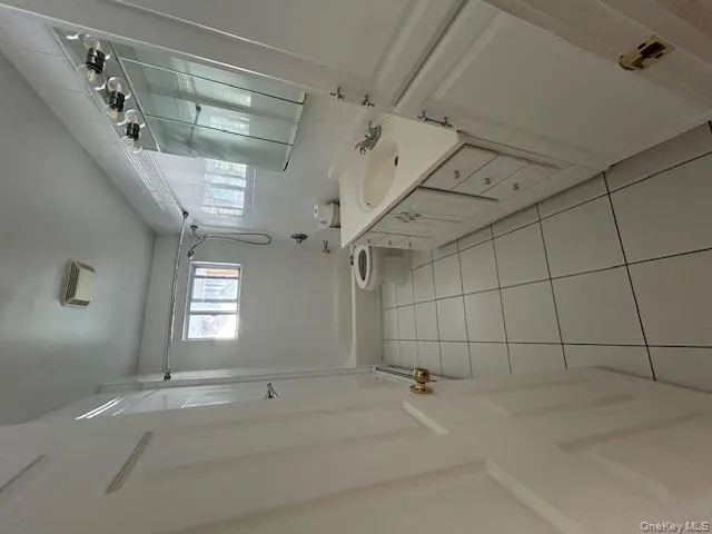 Full bathroom with shower / bathtub combination, vanity, light tile patterned floors, and a baseboard heating unit Full bathroom with shower / bathtub combination, vanity, light tile patterned floors, and a baseboard heating unit