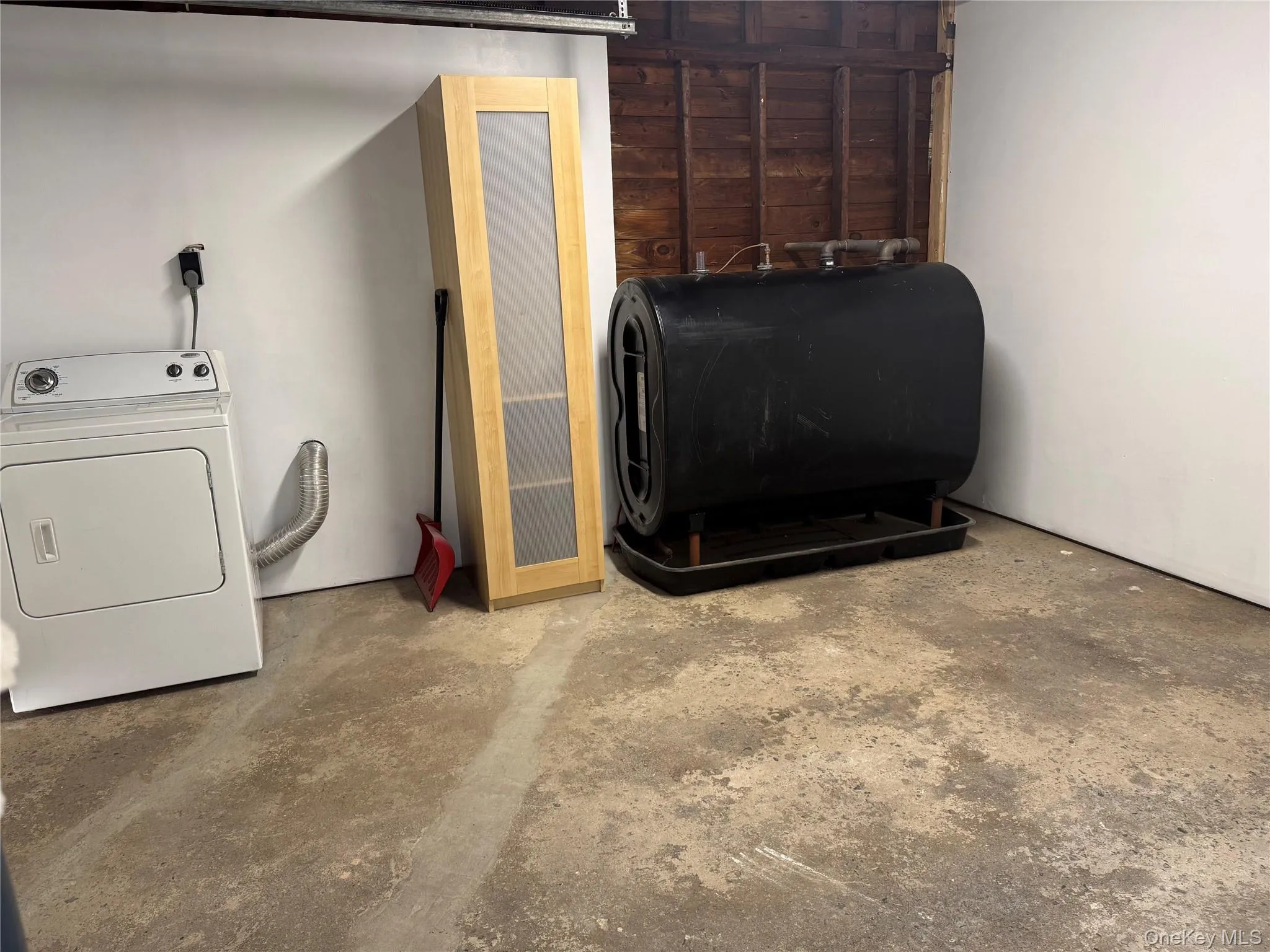 Laundry view of unfinished concrete floors, washer / dryer, and oil tank Laundry view of unfinished concrete floors, washer / dryer, and oil tank