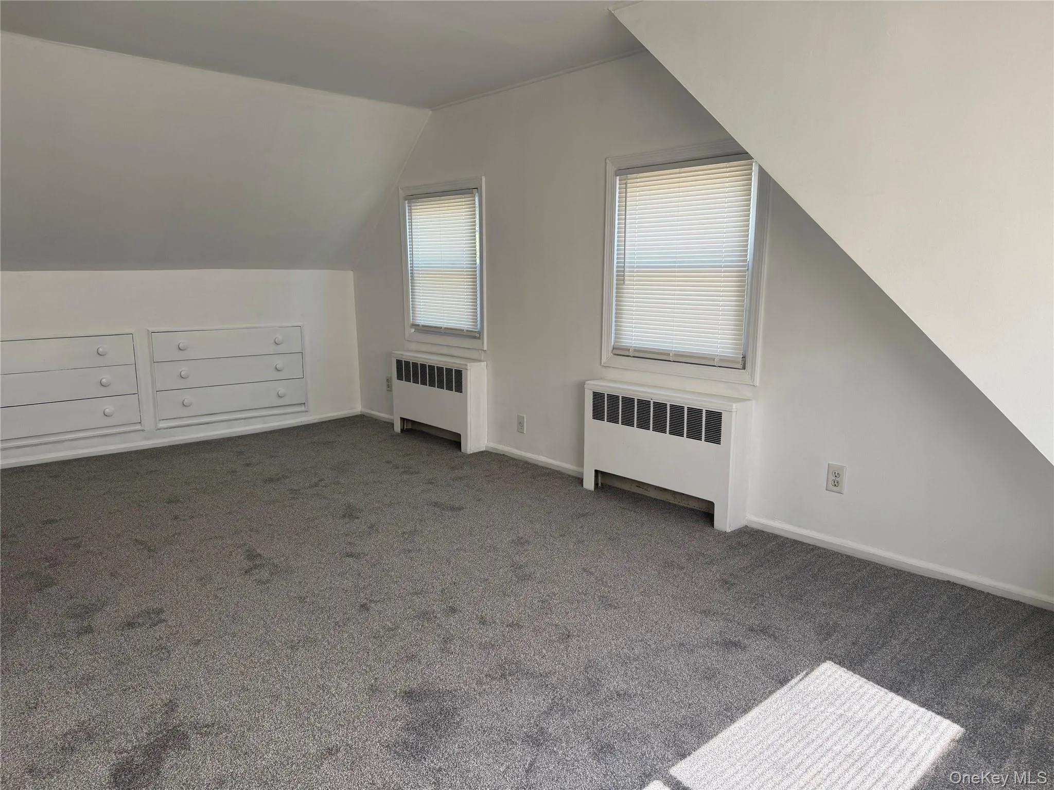 Bonus room with radiator, lofted ceiling, and carpet Bonus room with radiator, lofted ceiling, and carpet