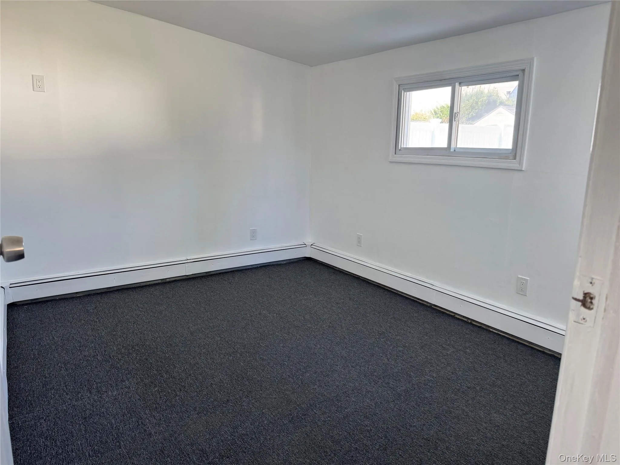 Empty room with carpet and baseboard heating Empty room with carpet and baseboard heating