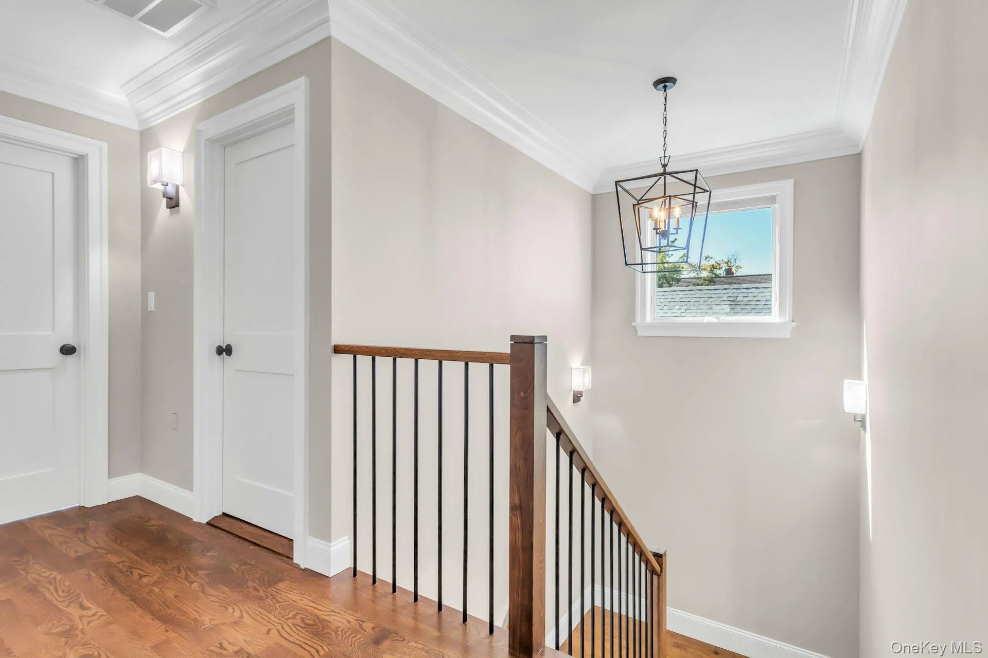 Hall featuring ornamental molding, wood finished floors, an upstairs landing, and a chandelier Hall featuring ornamental molding, wood finished floors, an upstairs landing, and a chandelier
