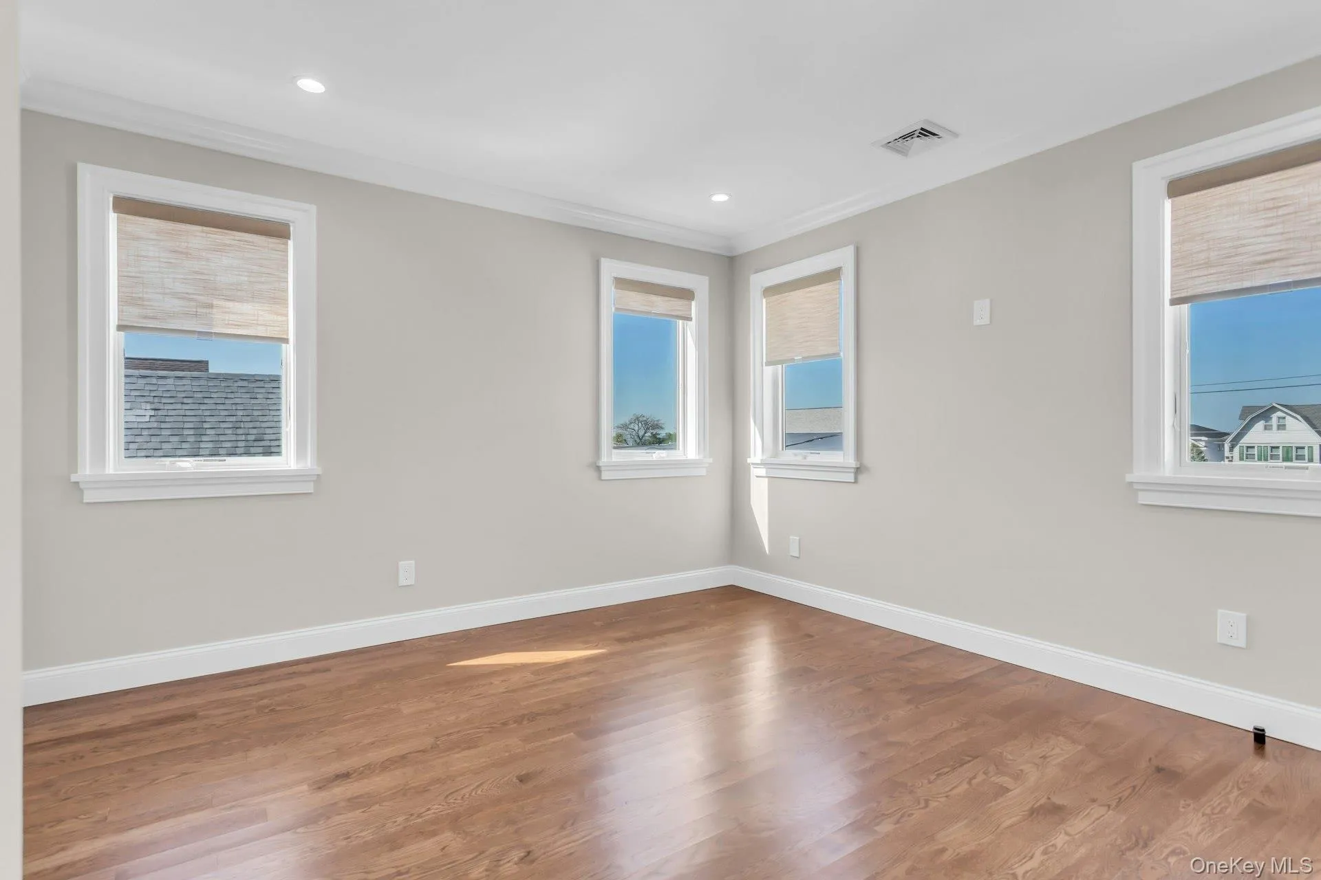 Unfurnished room with wood finished floors, ornamental molding, and recessed lighting Unfurnished room with wood finished floors, ornamental molding, and recessed lighting
