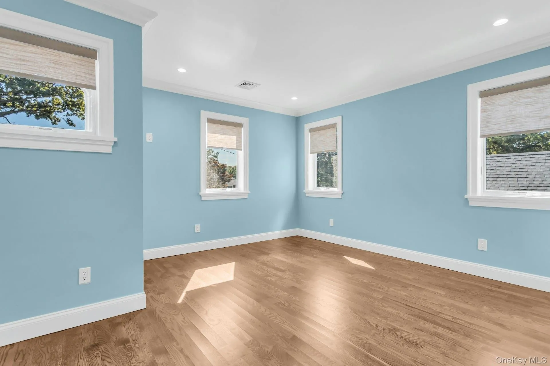 Empty room with wood finished floors, ornamental molding, and recessed lighting Empty room with wood finished floors, ornamental molding, and recessed lighting