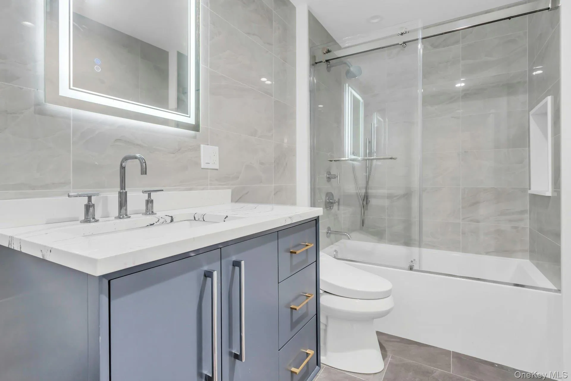 Bathroom featuring tile walls, enclosed tub / shower combo, vanity, and light tile patterned flooring Bathroom featuring tile walls, enclosed tub / shower combo, vanity, and light tile patterned flooring