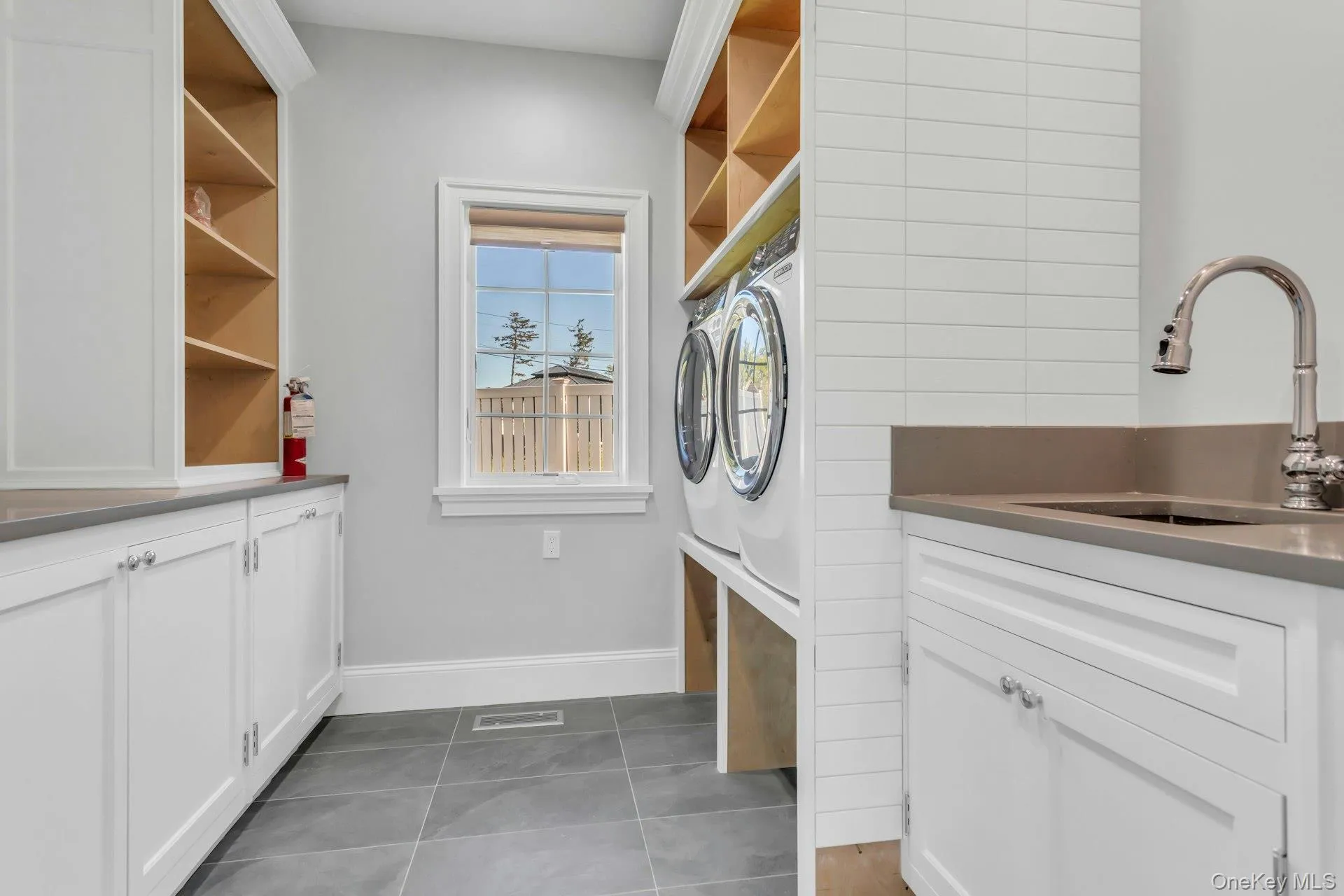 Washroom with dark tile patterned floors, cabinet space, and washer and clothes dryer Washroom with dark tile patterned floors, cabinet space, and washer and clothes dryer
