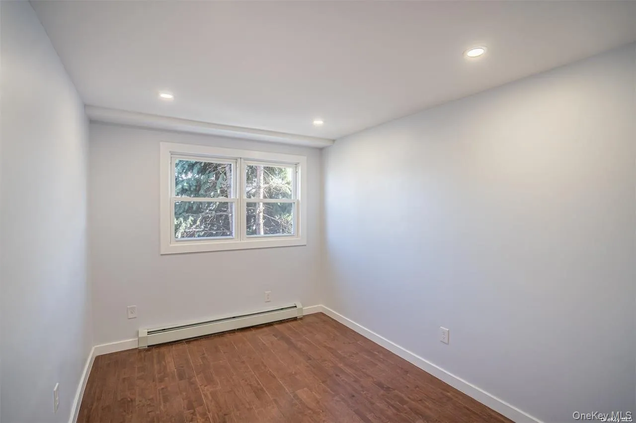 Spare room featuring dark wood-style floors, a baseboard radiator, and recessed lighting Spare room featuring dark wood-style floors, a baseboard radiator, and recessed lighting