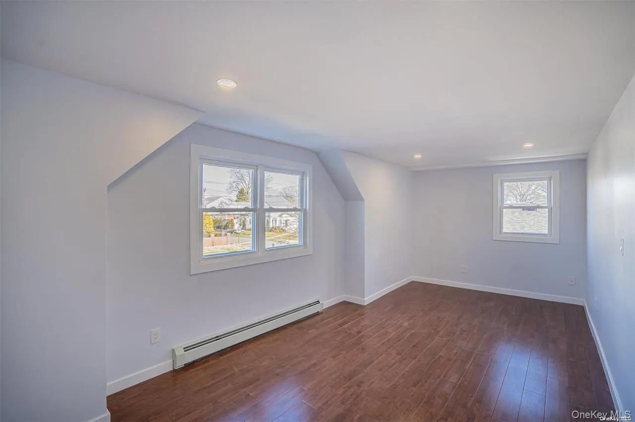 Additional living space with a baseboard heating unit, dark wood-style flooring, and recessed lighting Additional living space with a baseboard heating unit, dark wood-style flooring, and recessed lighting