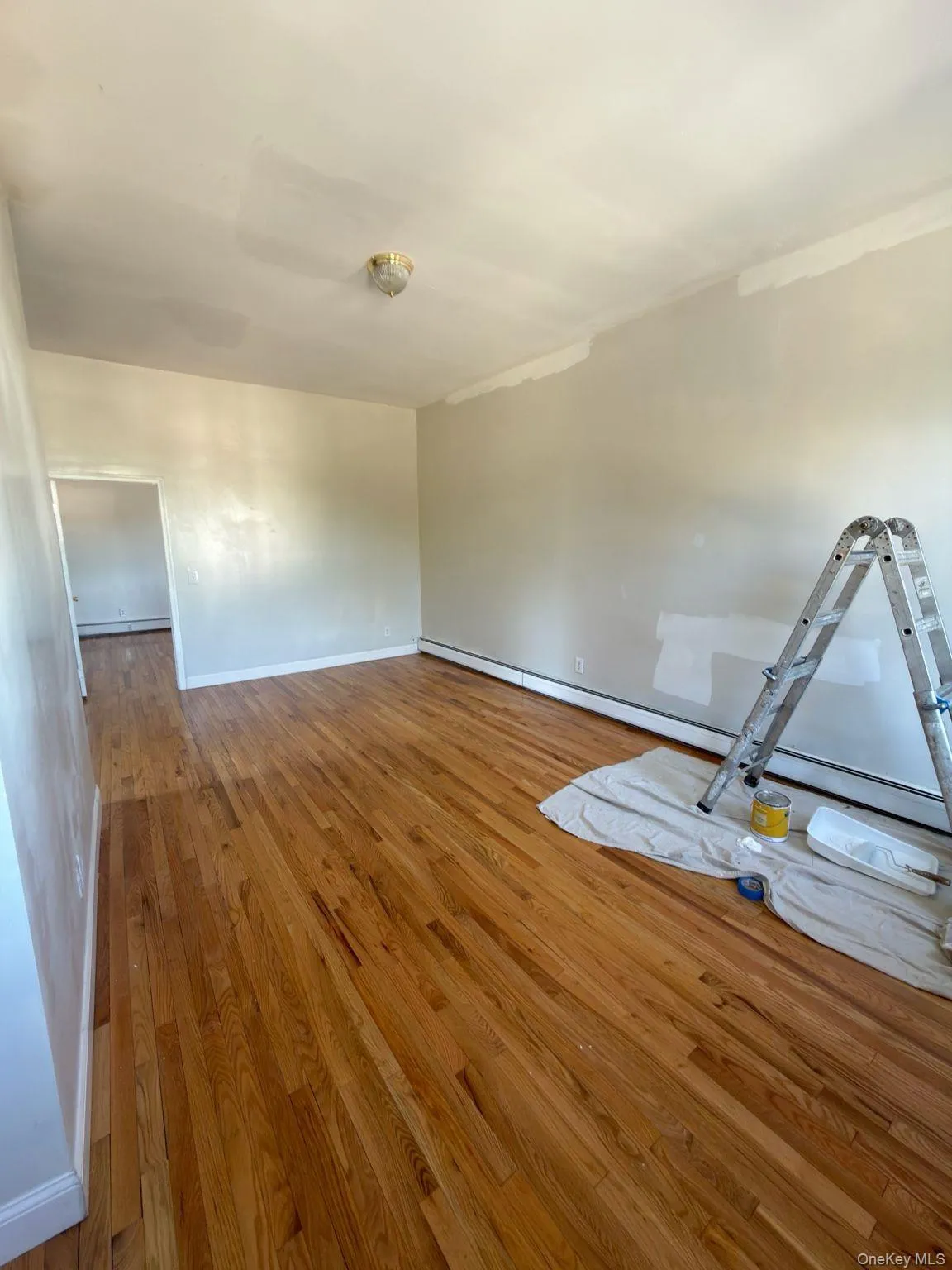 Empty room with wood finished floors and a baseboard heating unit Empty room with wood finished floors and a baseboard heating unit