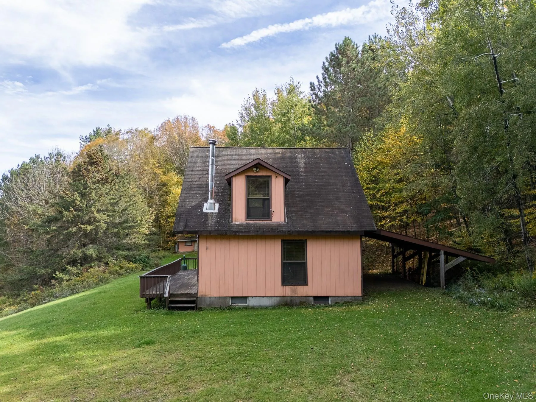 View of property exterior with a deck, a yard, and a forest view View of property exterior with a deck, a yard, and a forest view