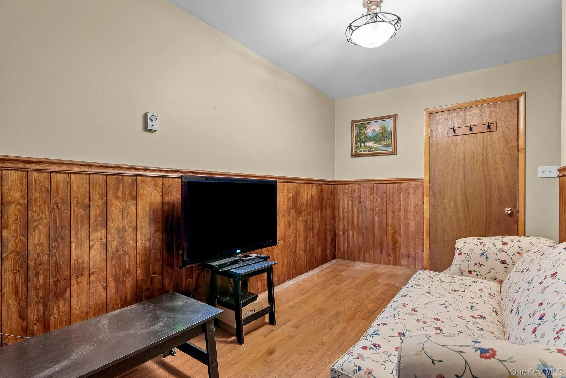 Living area featuring light wood-style floors, a wainscoted wall, and wood walls Living area featuring light wood-style floors, a wainscoted wall, and wood walls