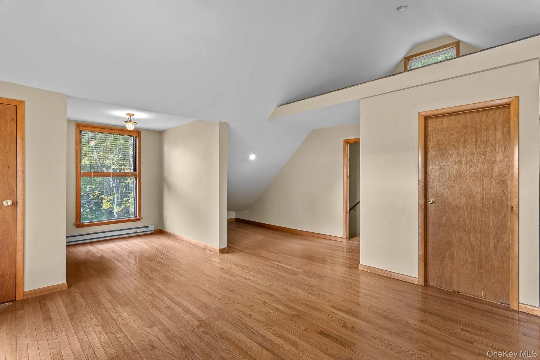 Bonus room with lofted ceiling, light wood finished floors, and a baseboard radiator Bonus room with lofted ceiling, light wood finished floors, and a baseboard radiator