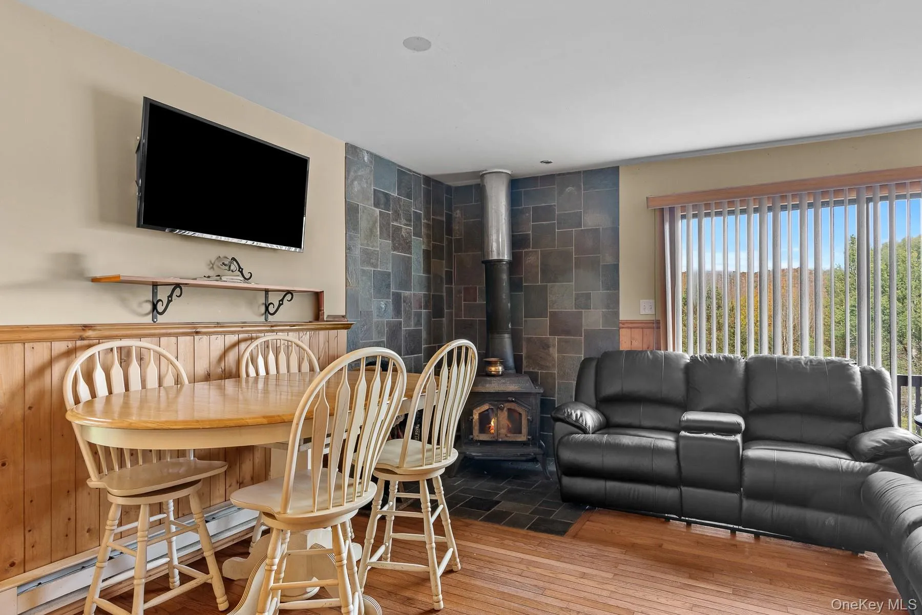 Dining area featuring a wood stove, a baseboard heating unit, and hardwood / wood-style flooring Dining area featuring a wood stove, a baseboard heating unit, and hardwood / wood-style flooring