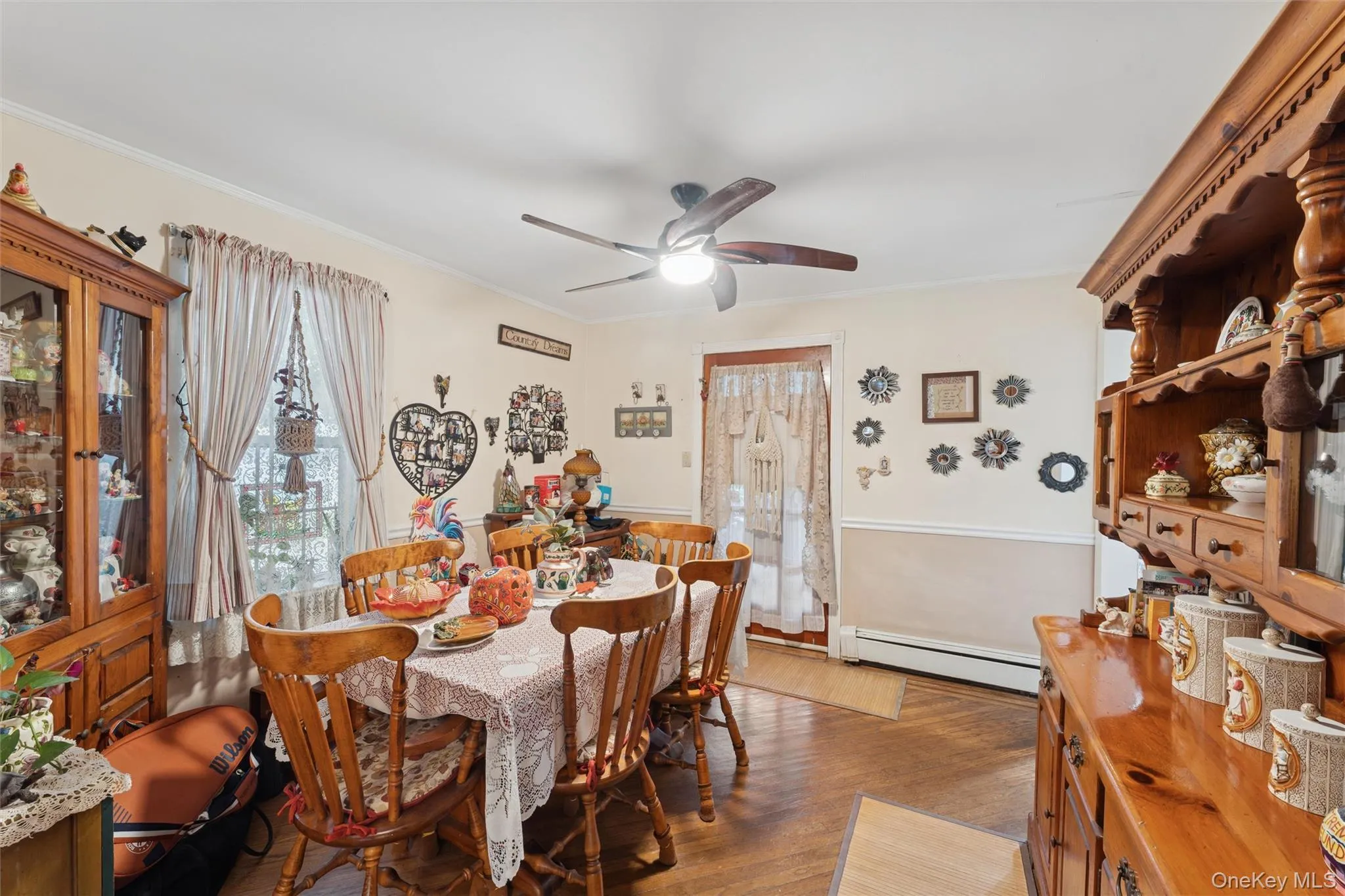 Dining room featuring dark wood-style flooring, baseboard heating, crown molding, and ceiling fan Dining room featuring dark wood-style flooring, baseboard heating, crown molding, and ceiling fan