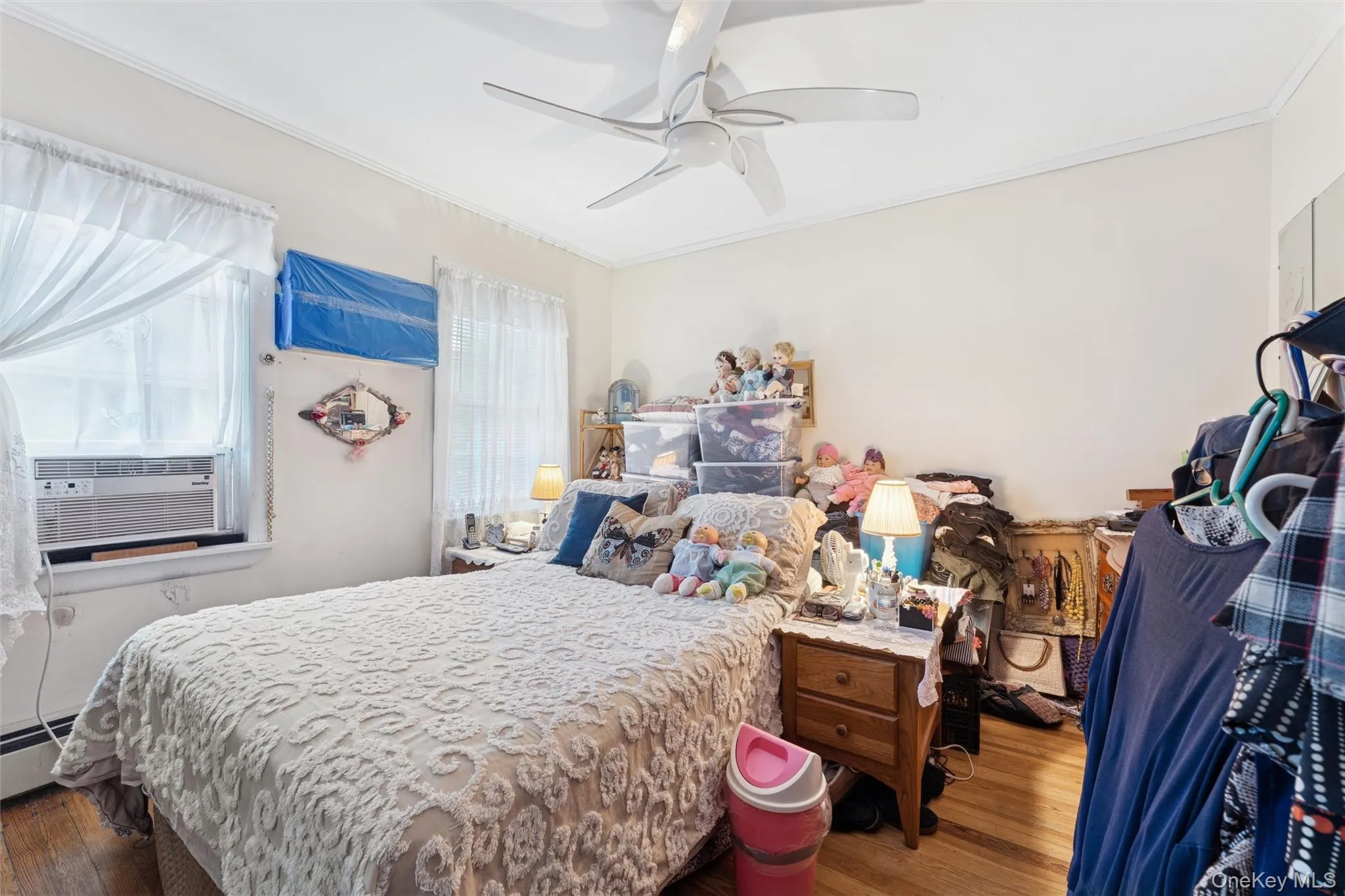 Bedroom featuring crown molding, wood finished floors, cooling unit, ceiling fan, and baseboard heating Bedroom featuring crown molding, wood finished floors, cooling unit, ceiling fan, and baseboard heating