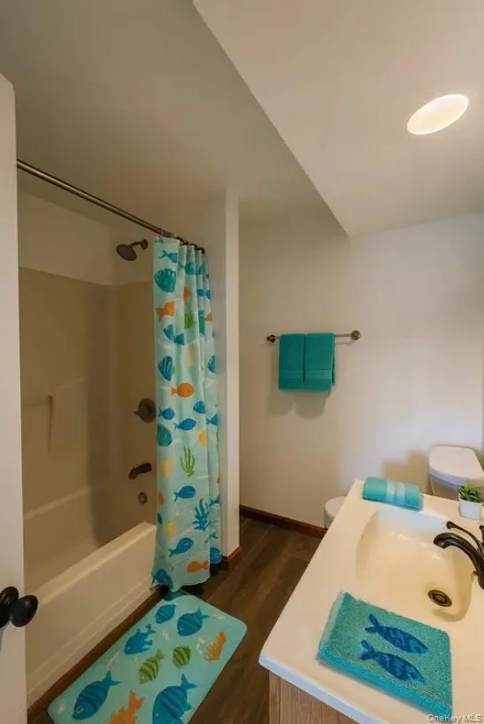 Full bath featuring dark wood finished floors, shower / bath combination with curtain, and vanity Full bath featuring dark wood finished floors, shower / bath combination with curtain, and vanity