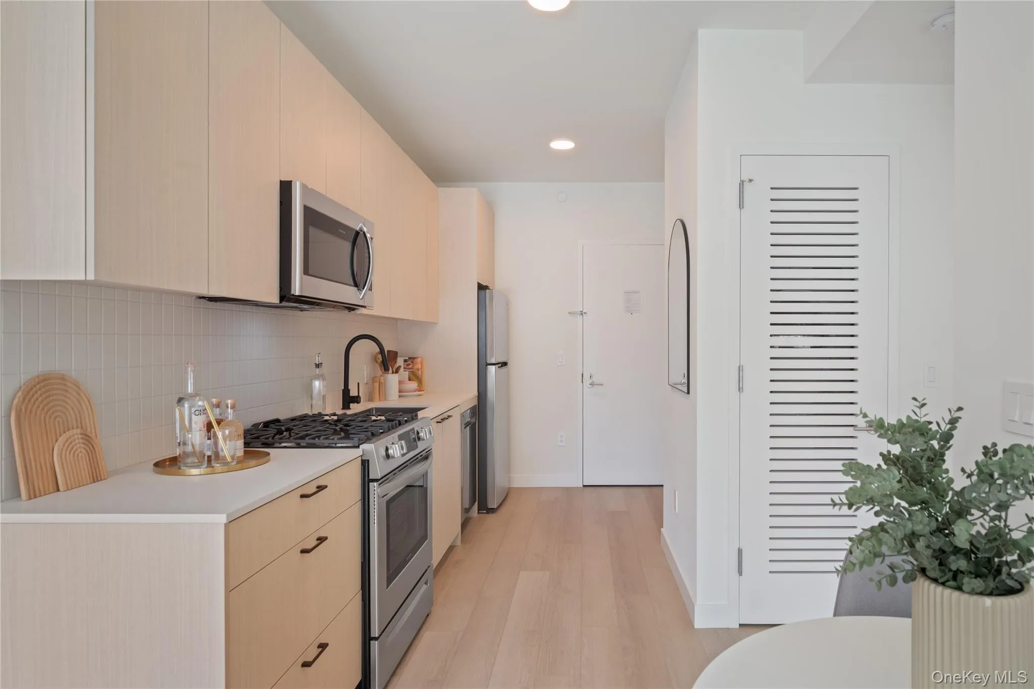 Kitchen featuring stainless steel appliances, modern cabinets, light brown cabinets, recessed lighting, and light wood finished floors Kitchen featuring stainless steel appliances, modern cabinets, light brown cabinets, recessed lighting, and light wood finished floors