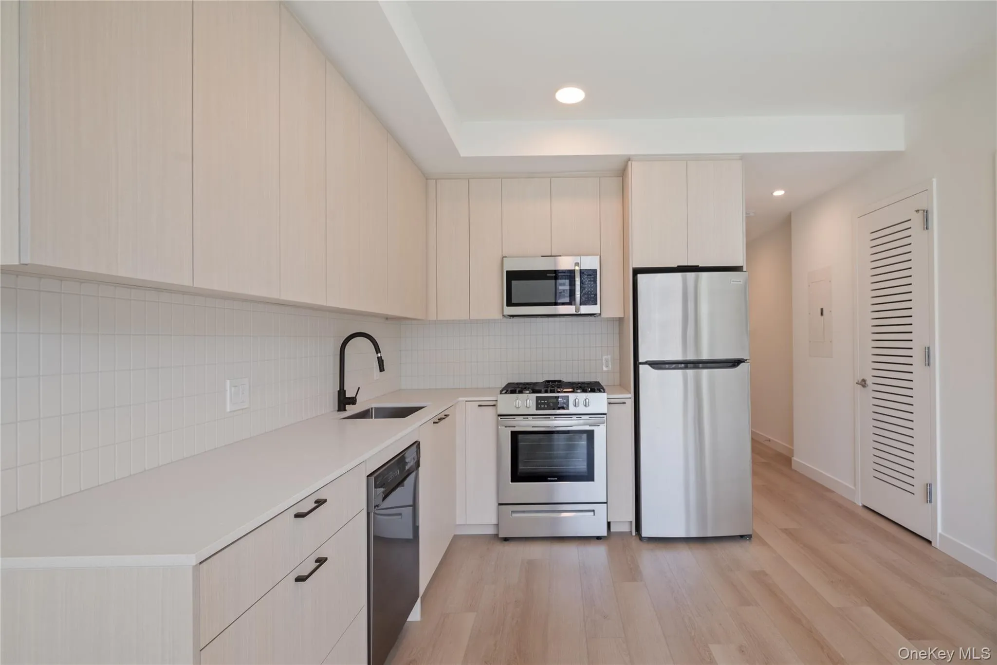 Kitchen with appliances with stainless steel finishes, light wood-style floors, backsplash, modern cabinets, and recessed lighting Kitchen with appliances with stainless steel finishes, light wood-style floors, backsplash, modern cabinets, and recessed lighting