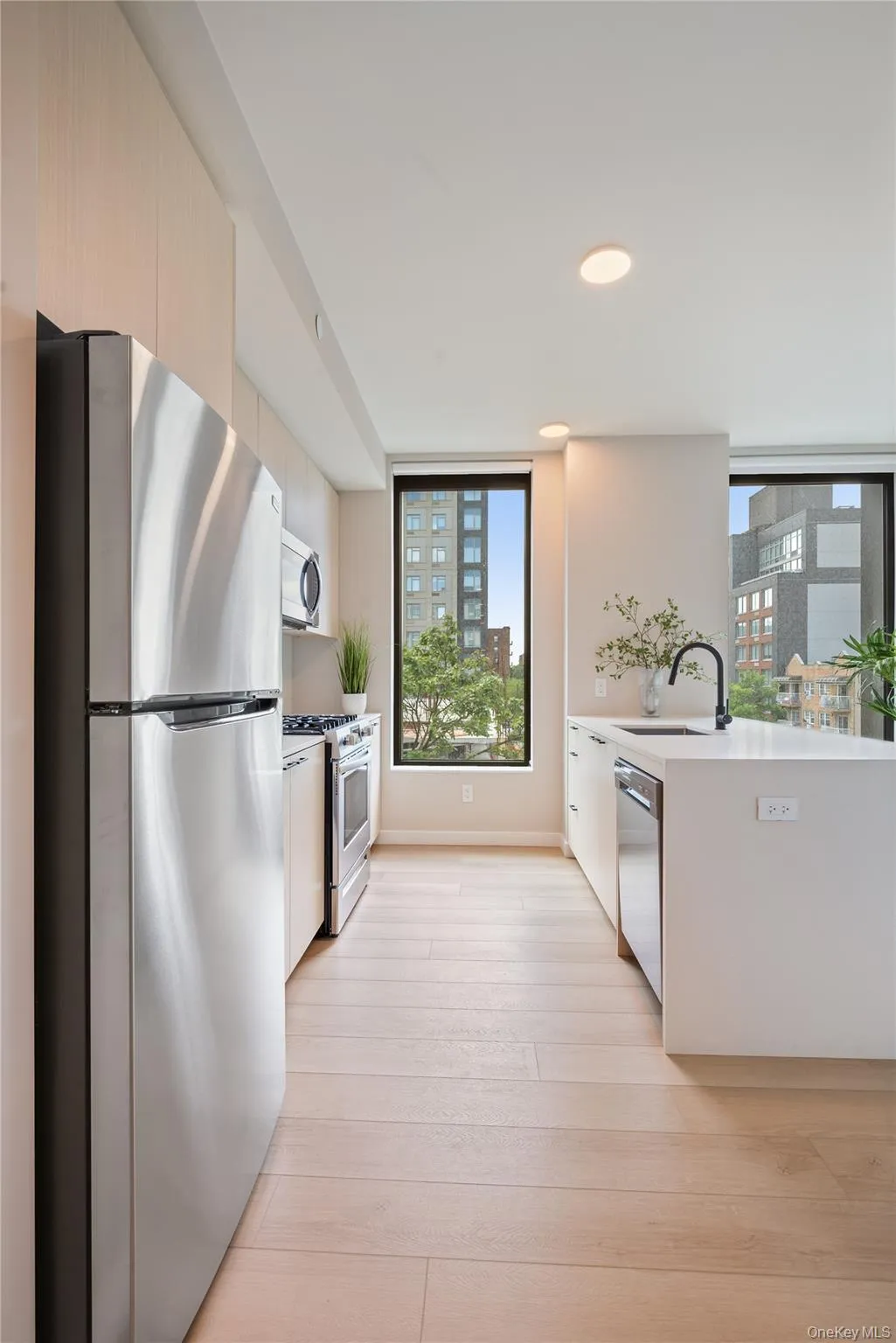 Kitchen with appliances with stainless steel finishes, light wood-style floors, a peninsula, light stone countertops, and modern cabinets Kitchen with appliances with stainless steel finishes, light wood-style floors, a peninsula, light stone countertops, and modern cabinets