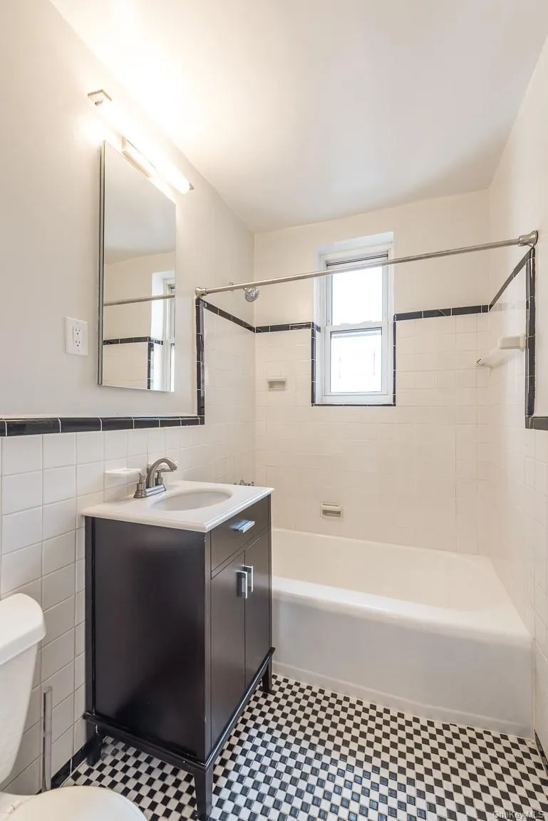 Bathroom with tile walls, tub / shower combination, vanity, and wainscoting Bathroom with tile walls, tub / shower combination, vanity, and wainscoting