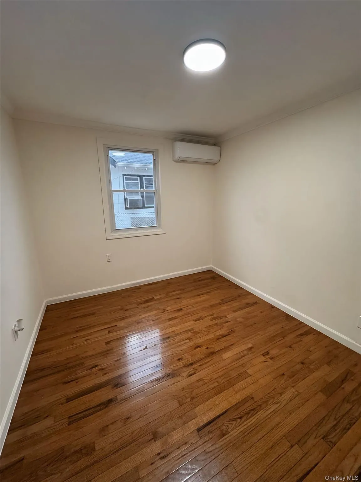 Unfurnished room with dark wood-style flooring, crown molding, and a wall mounted AC Unfurnished room with dark wood-style flooring, crown molding, and a wall mounted AC
