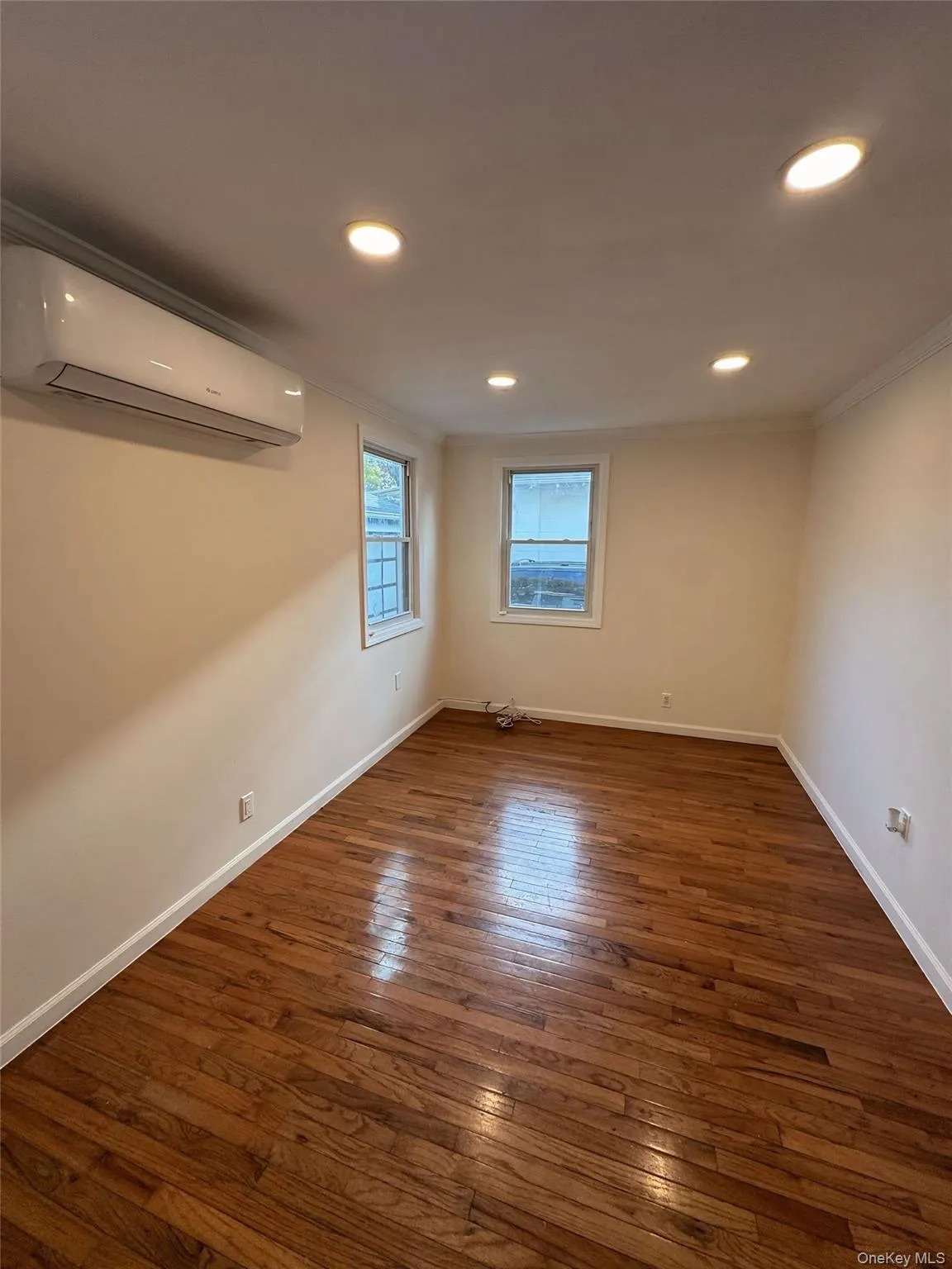 Empty room with dark wood-style flooring, a wall unit AC, recessed lighting, and ornamental molding Empty room with dark wood-style flooring, a wall unit AC, recessed lighting, and ornamental molding