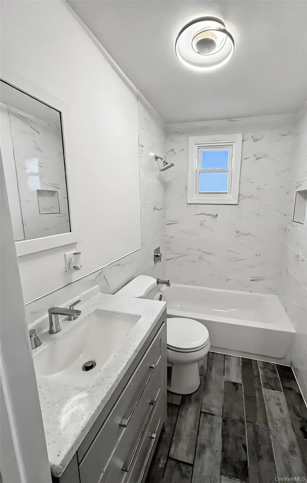 Bathroom with vanity, washtub / shower combination, and wood finish floors Bathroom with vanity, washtub / shower combination, and wood finish floors