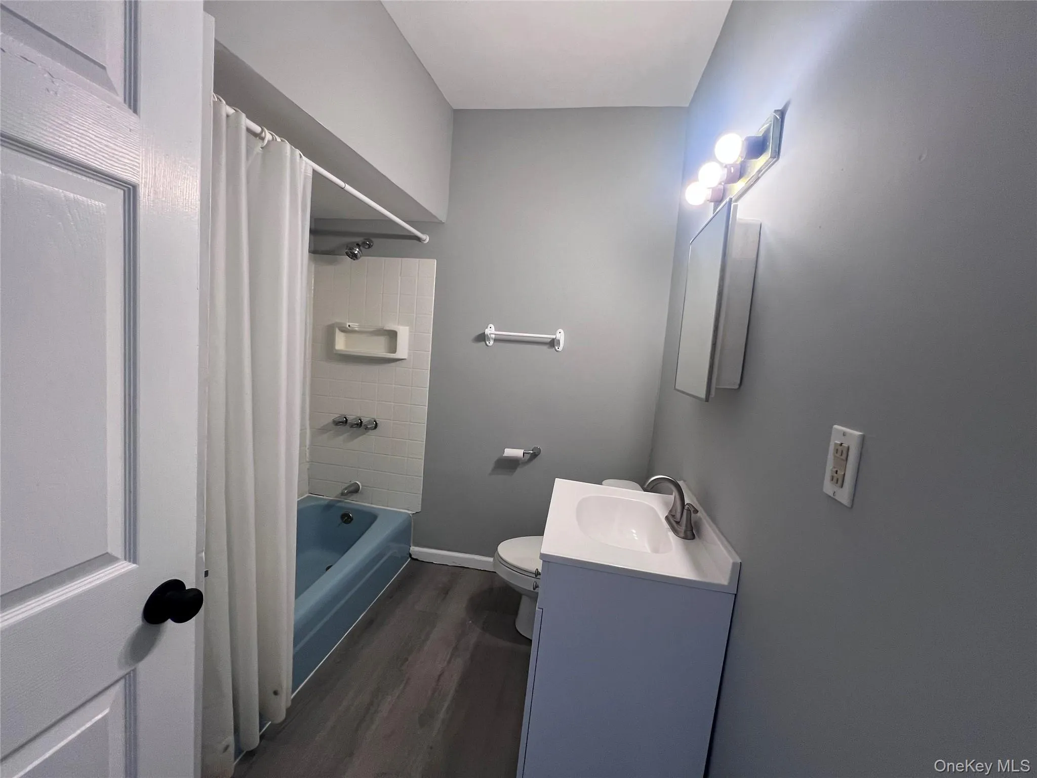 Bathroom with vanity, dark wood-type flooring, and shower / bath combination with curtain Bathroom with vanity, dark wood-type flooring, and shower / bath combination with curtain