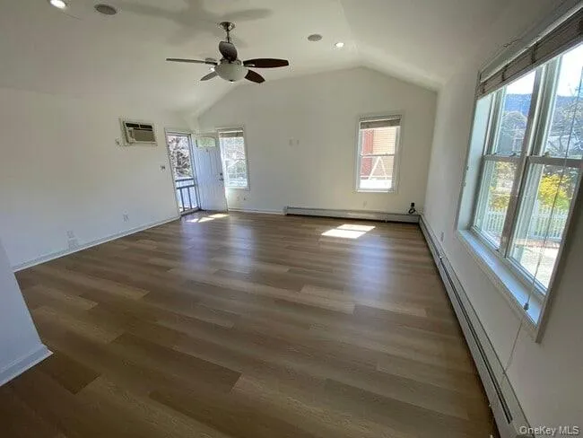 Spare room featuring a baseboard heating unit, vaulted ceiling, dark wood-style flooring, recessed lighting, and baseboard heating Spare room featuring a baseboard heating unit, vaulted ceiling, dark wood-style flooring, recessed lighting, and baseboard heating