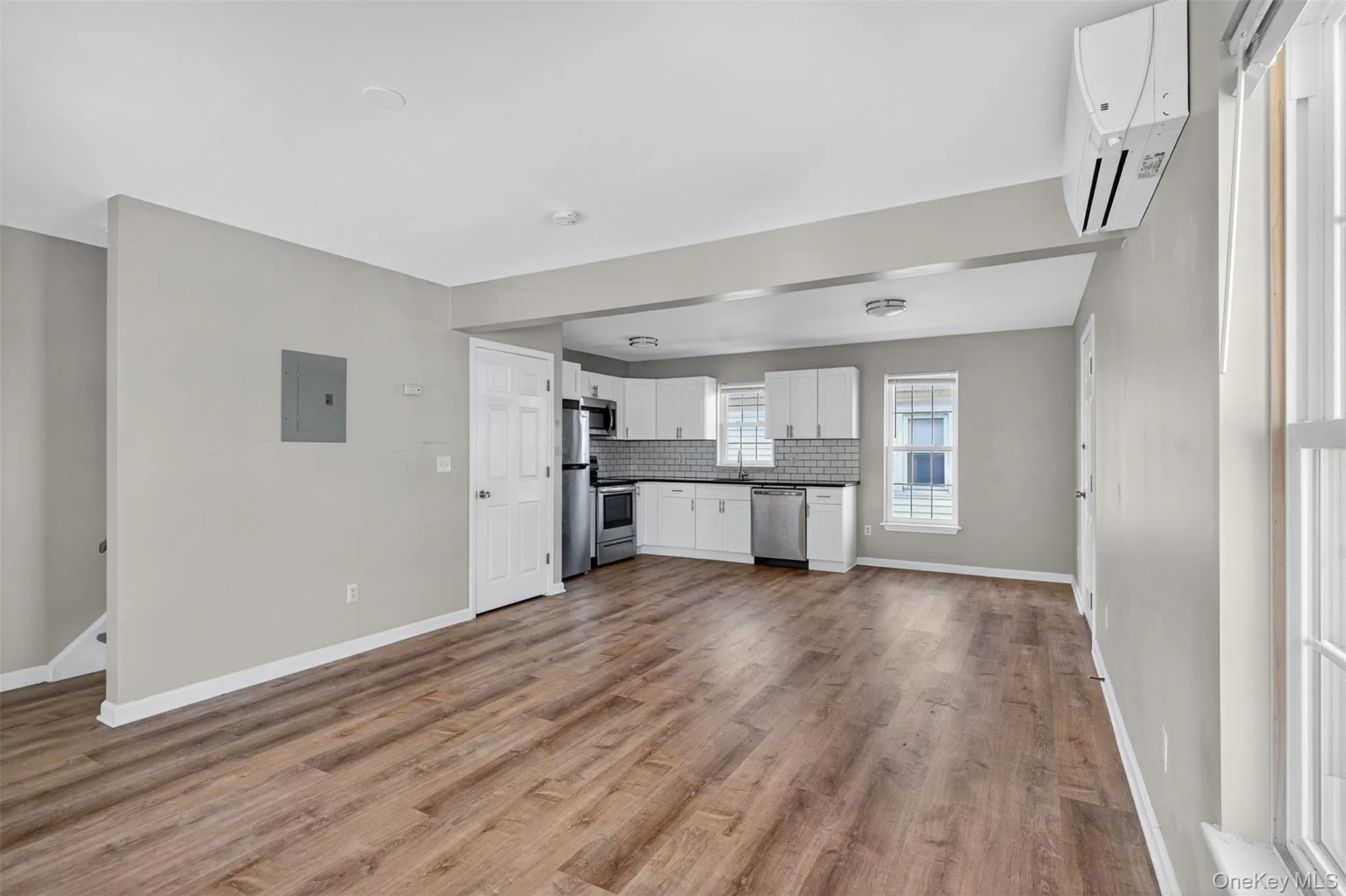 Kitchen with dark countertops, white cabinets, open floor plan, backsplash, and appliances with stainless steel finishes Kitchen with dark countertops, white cabinets, open floor plan, backsplash, and appliances with stainless steel finishes